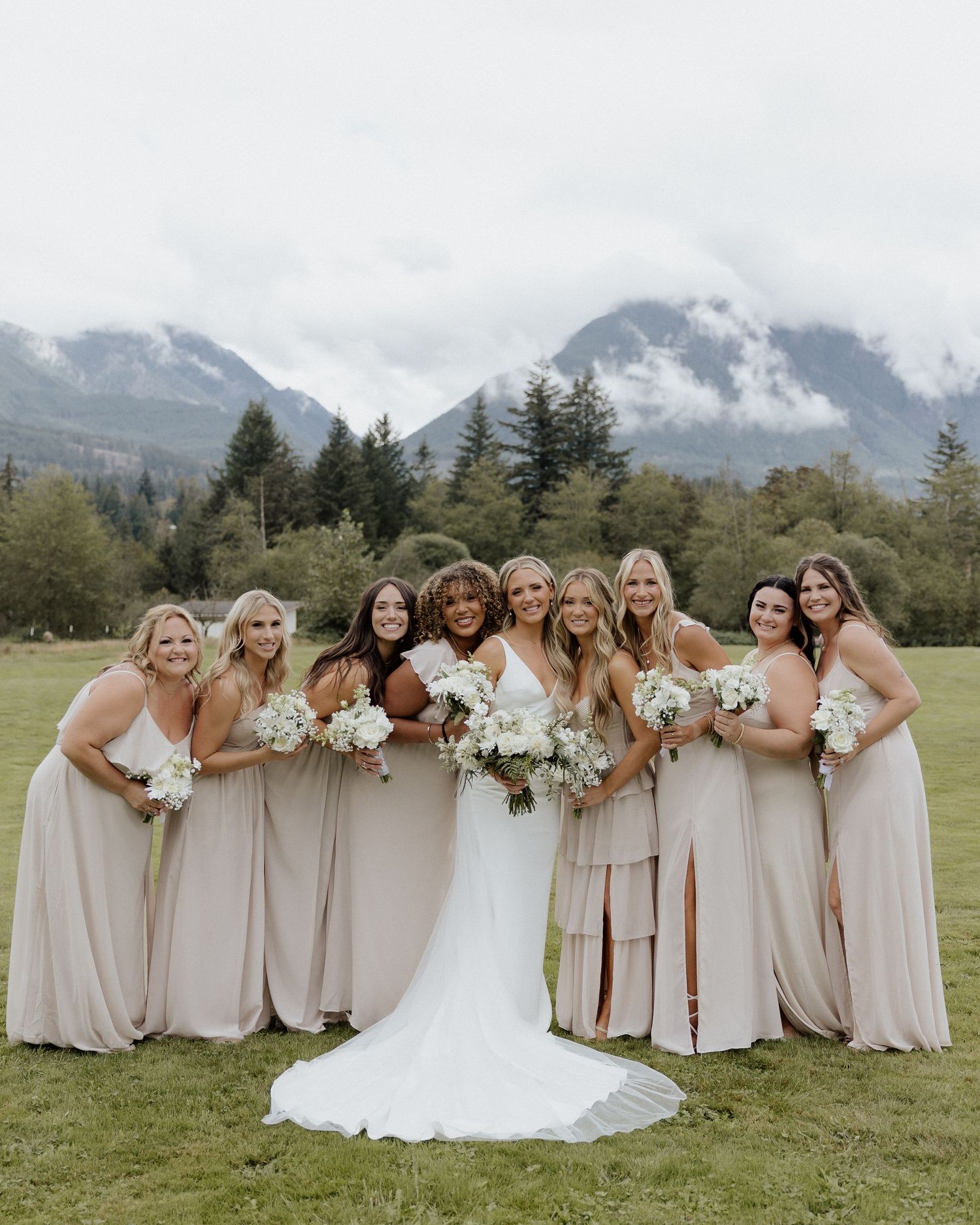 Joyful bridal party group photo with mountains and evergreens in background.
