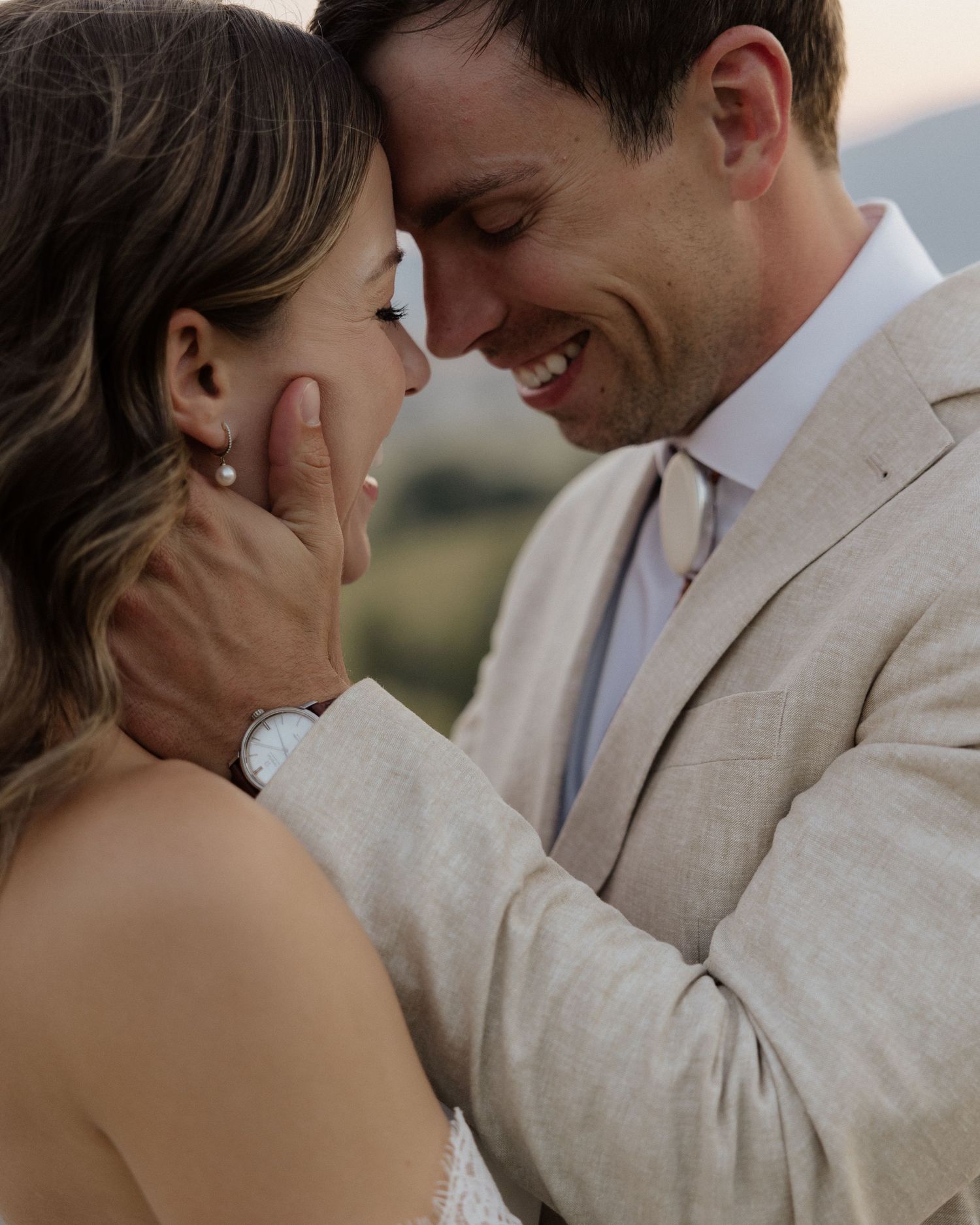 Intimate moment between newlyweds as they share a tender touch against mountain backdrop.
