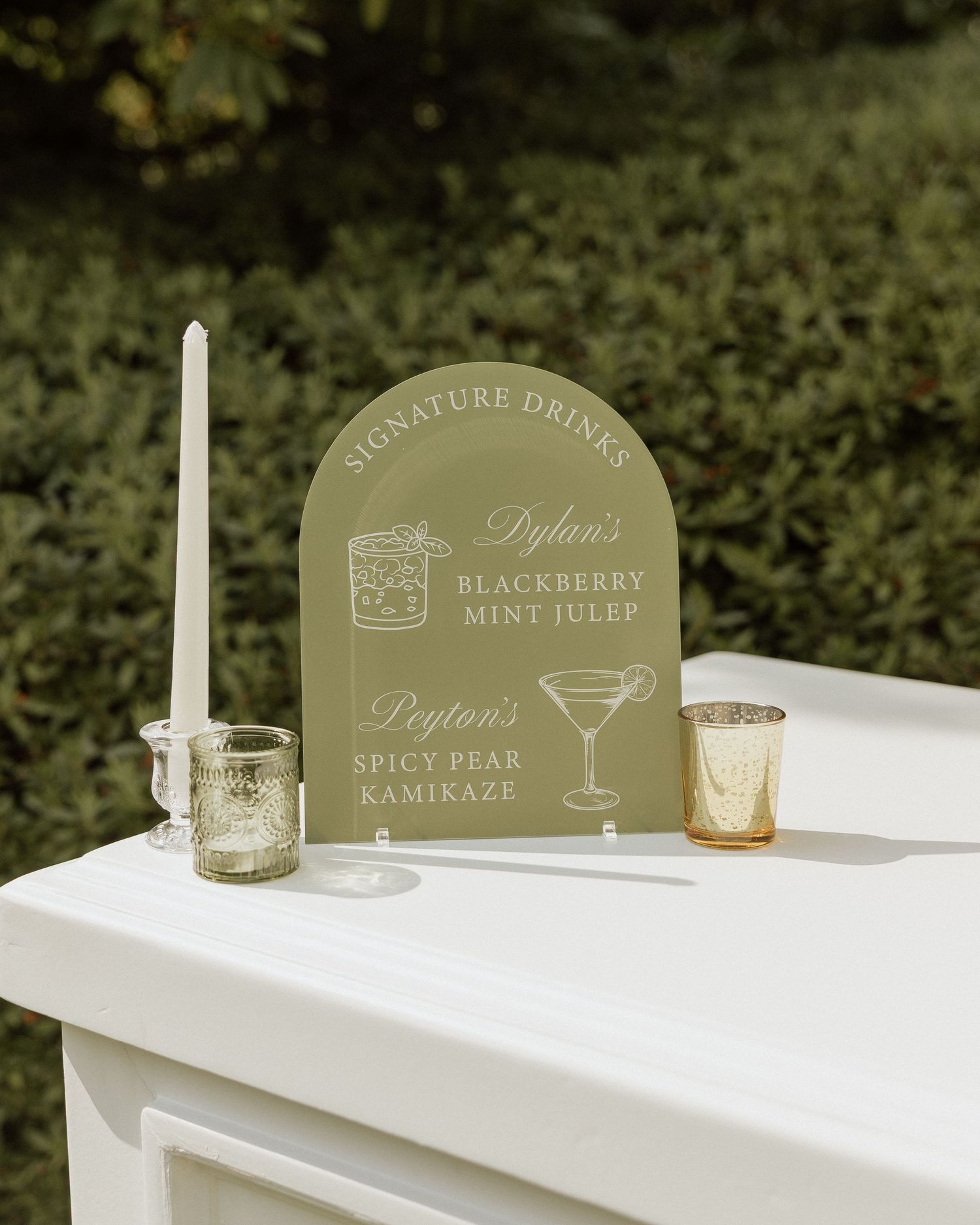 Sage green acrylic arch wedding signature drinks sign featuring Dylan's Blackberry Mint Julep and Peyton's Spicy Pear Kamikaze.