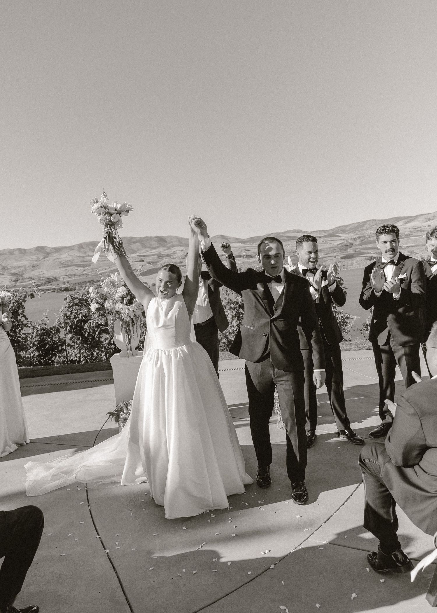 Newlyweds raise hands in celebration as they walk back down the aisle after ceremony.