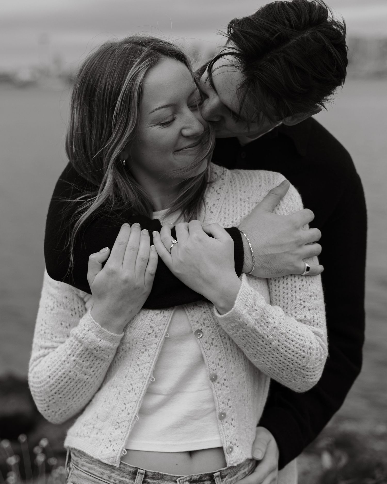 A romantic black and white photo of a couple sharing an intimate embrace with a blurred background.