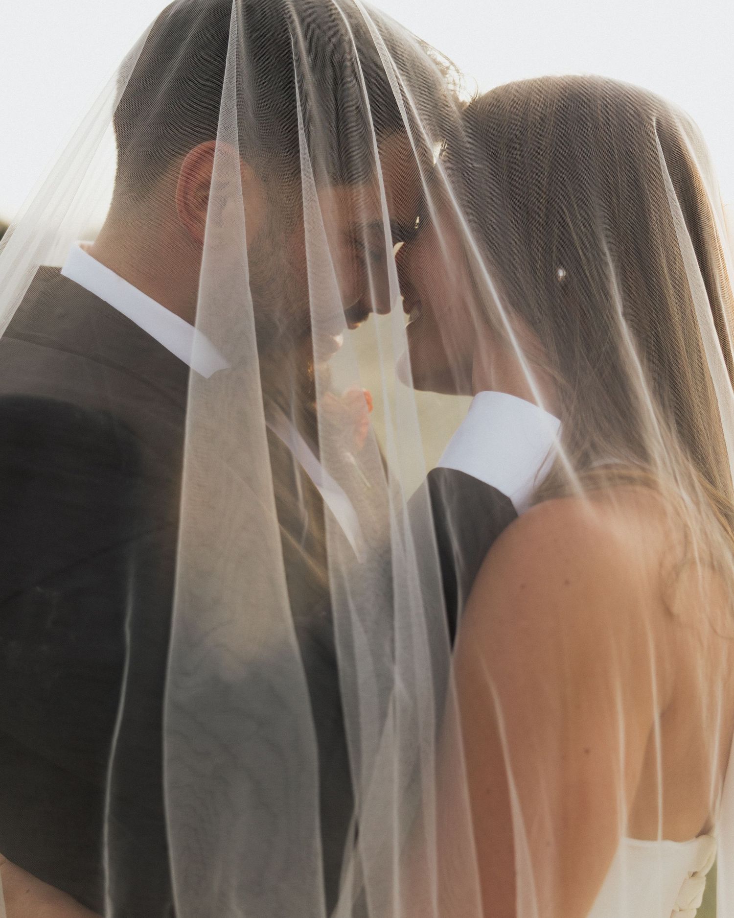 Close-up shot of bridal veils flowing in sunlight creating ethereal atmosphere.