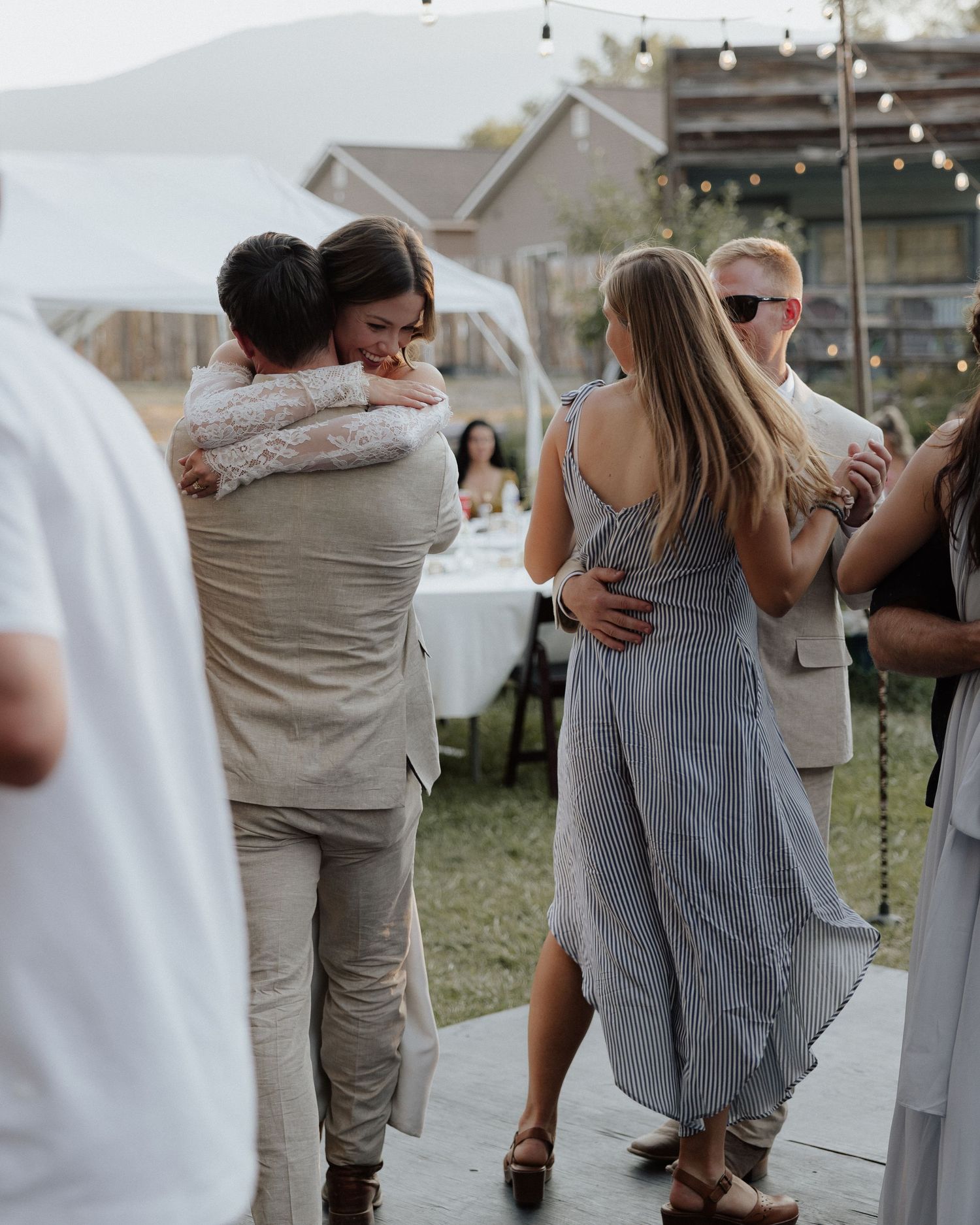 Wedding celebration on outdoor dance floor with guests in summer attire.