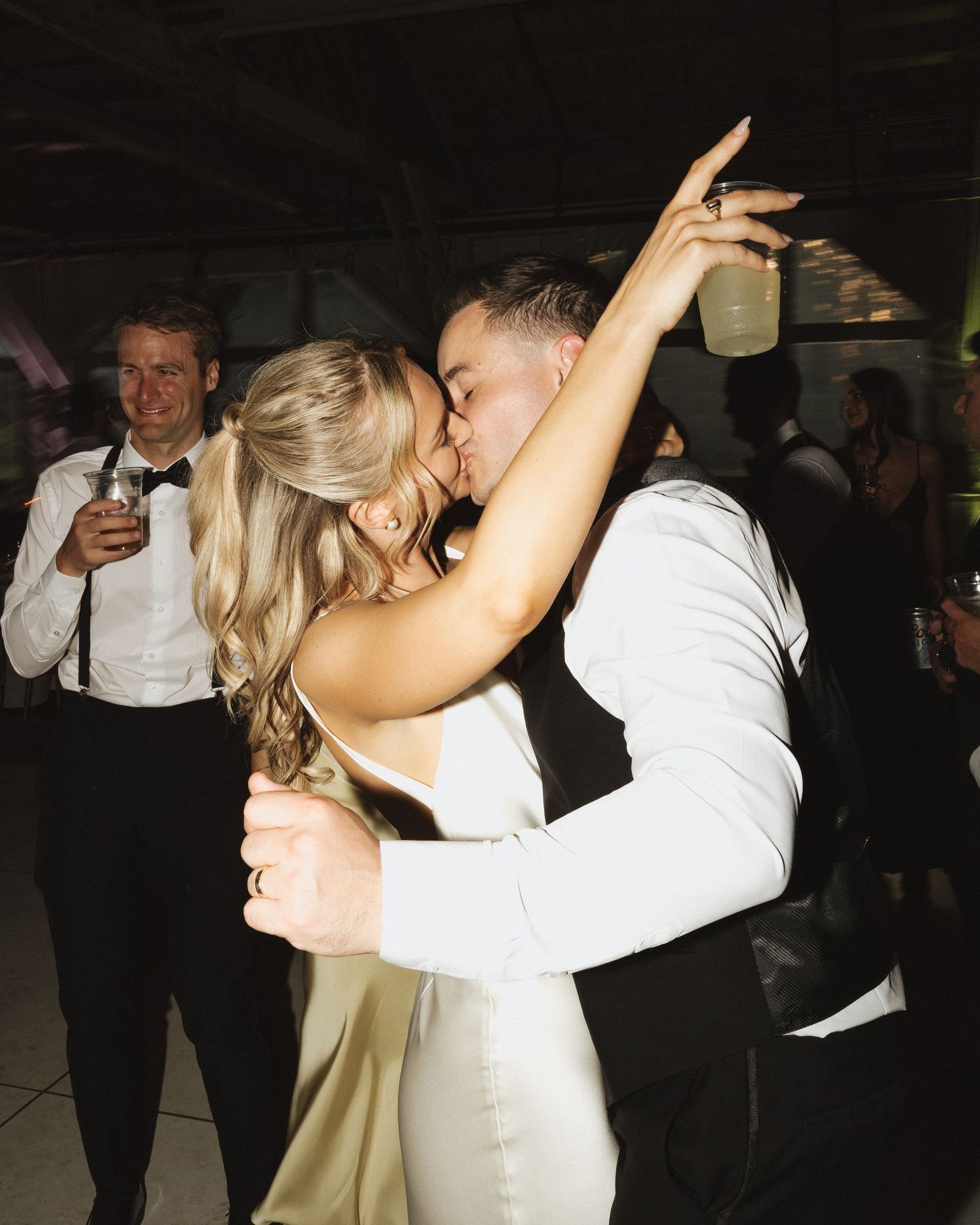 Bride and groom share a passionate kiss on the dance floor during their wedding reception.