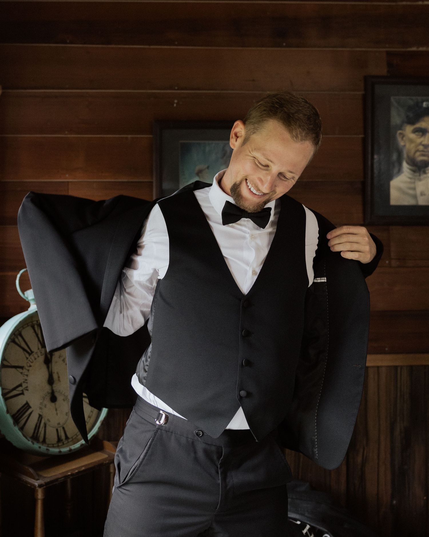 Person adjusting formal black tuxedo vest while getting ready.