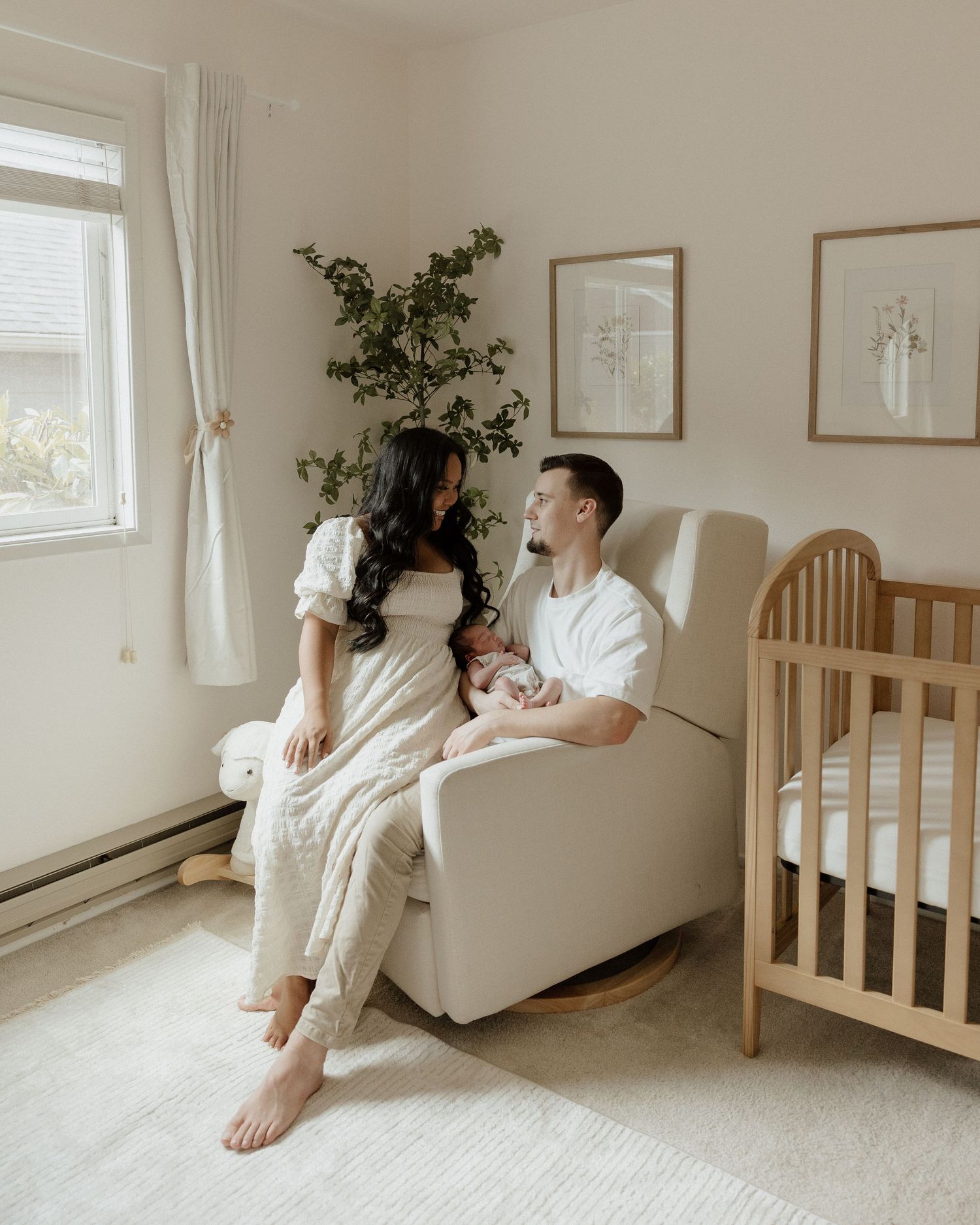 Family moment in bright nursery with wooden crib and white furniture.