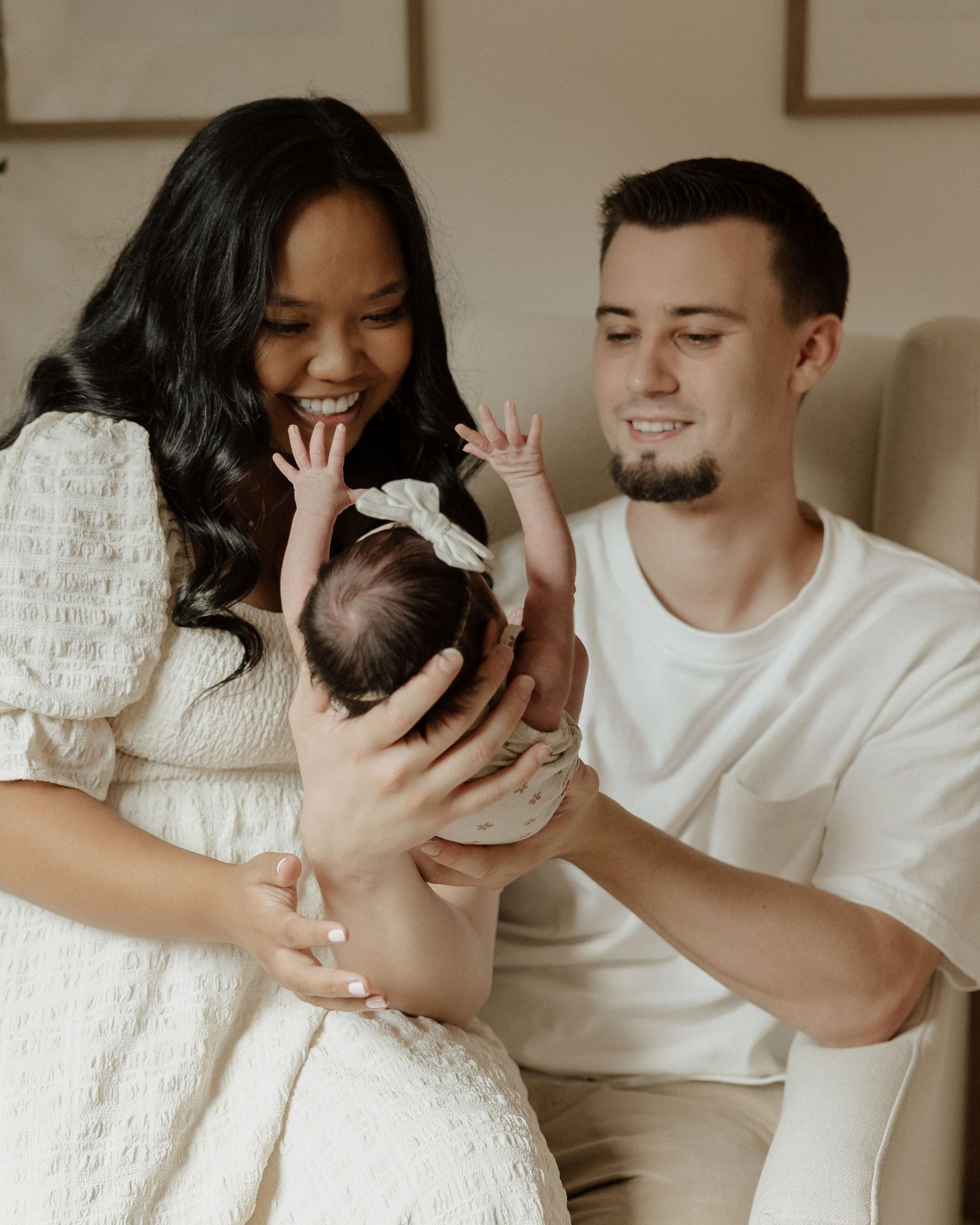 Happy family moment with newborn baby in white nursery setting.