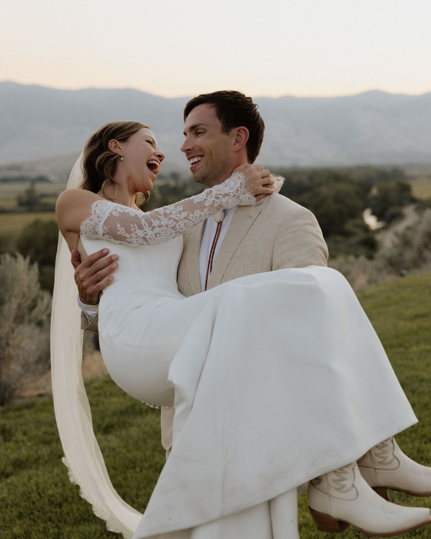 Candid wedding portrait showing joy and laughter against a mountain landscape.