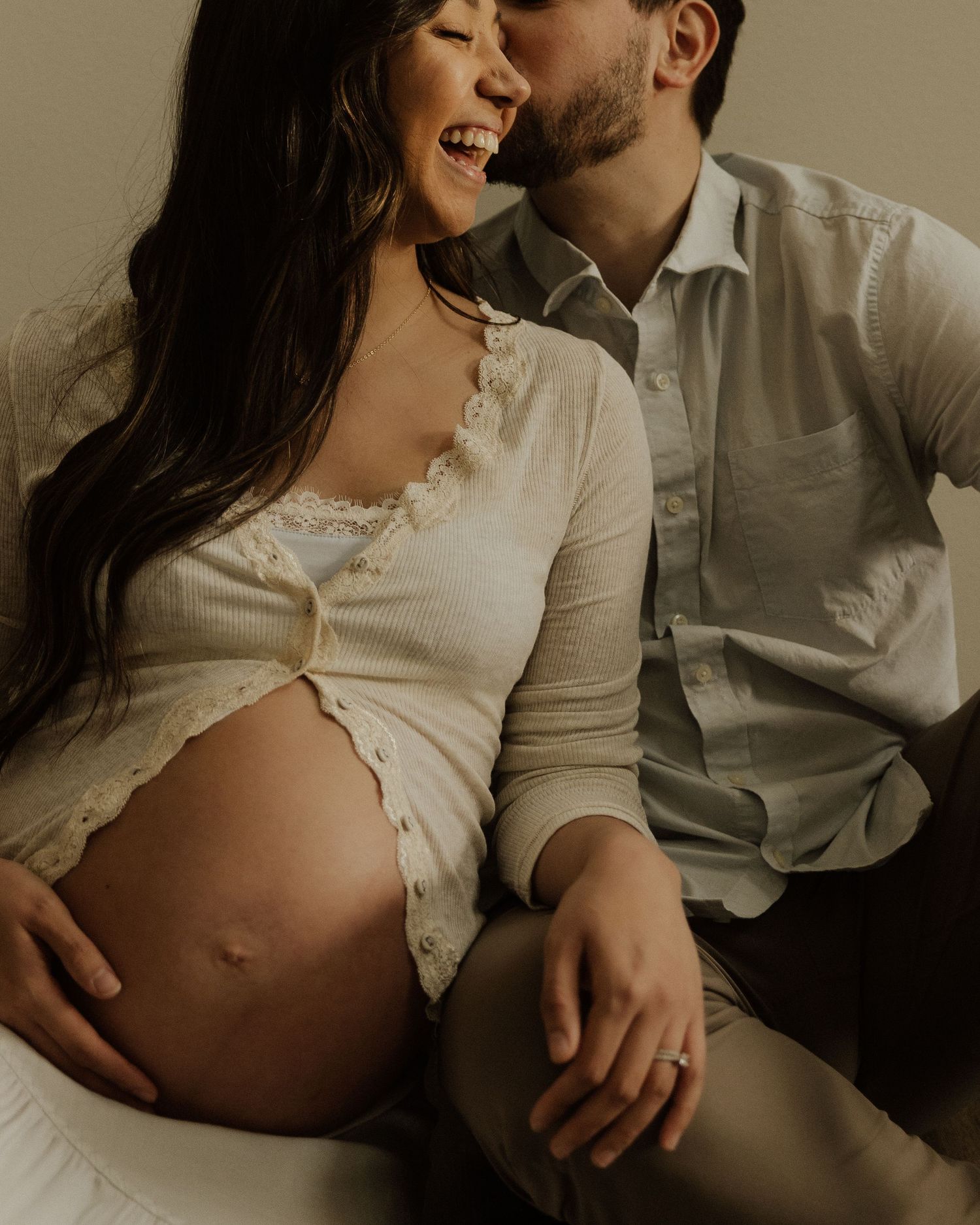 Intimate maternity moment captured in warm tones with cream colored clothing.