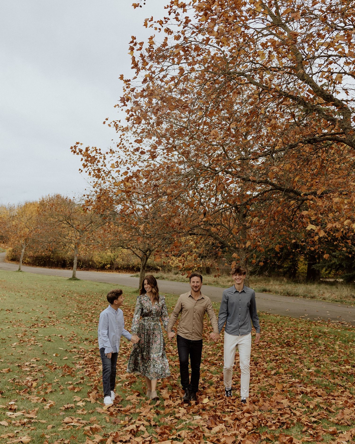 Four people walking together on a path surrounded by fall foliage and golden trees.