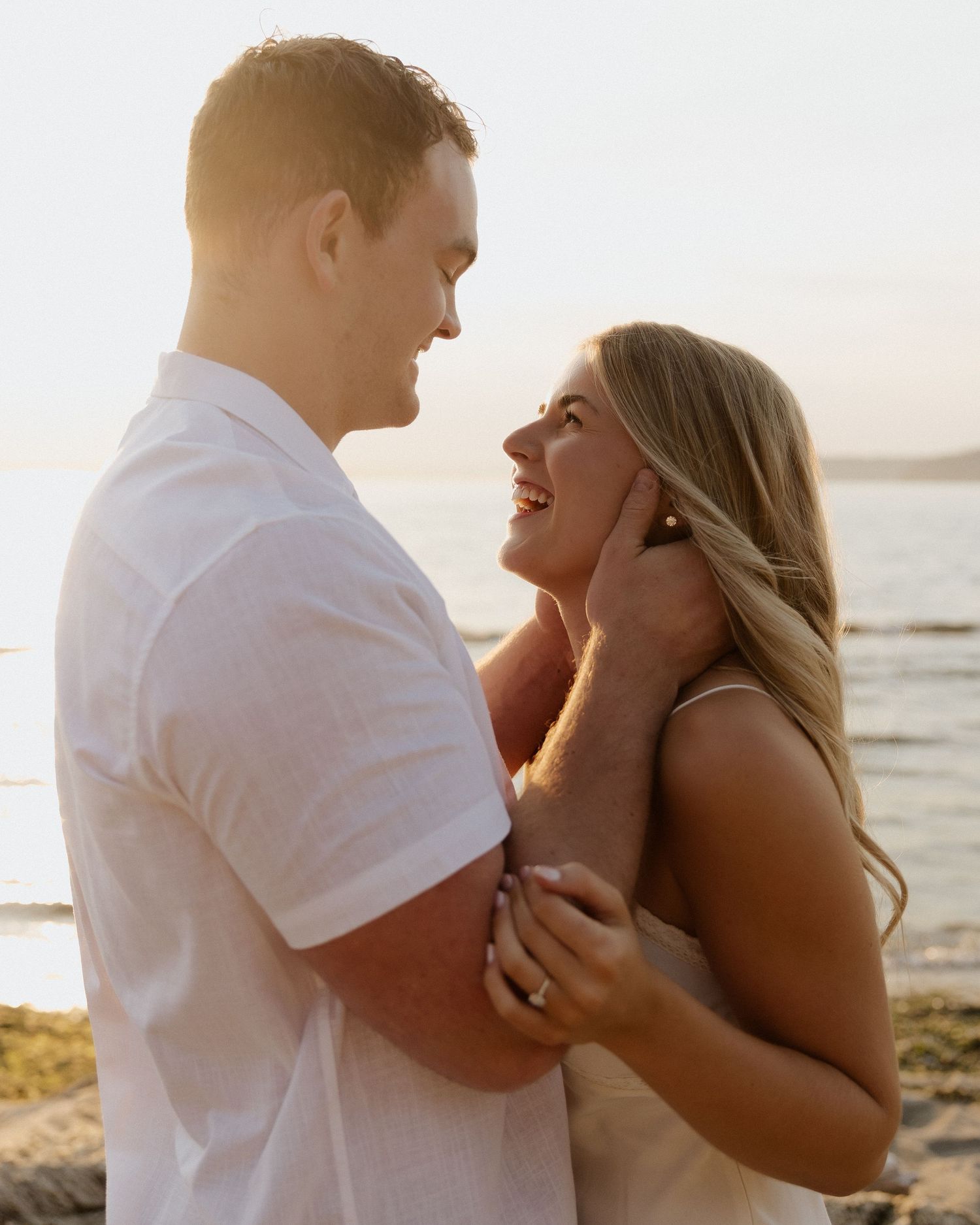 A romantic beach portrait of a couple sharing a tender moment at sunset.