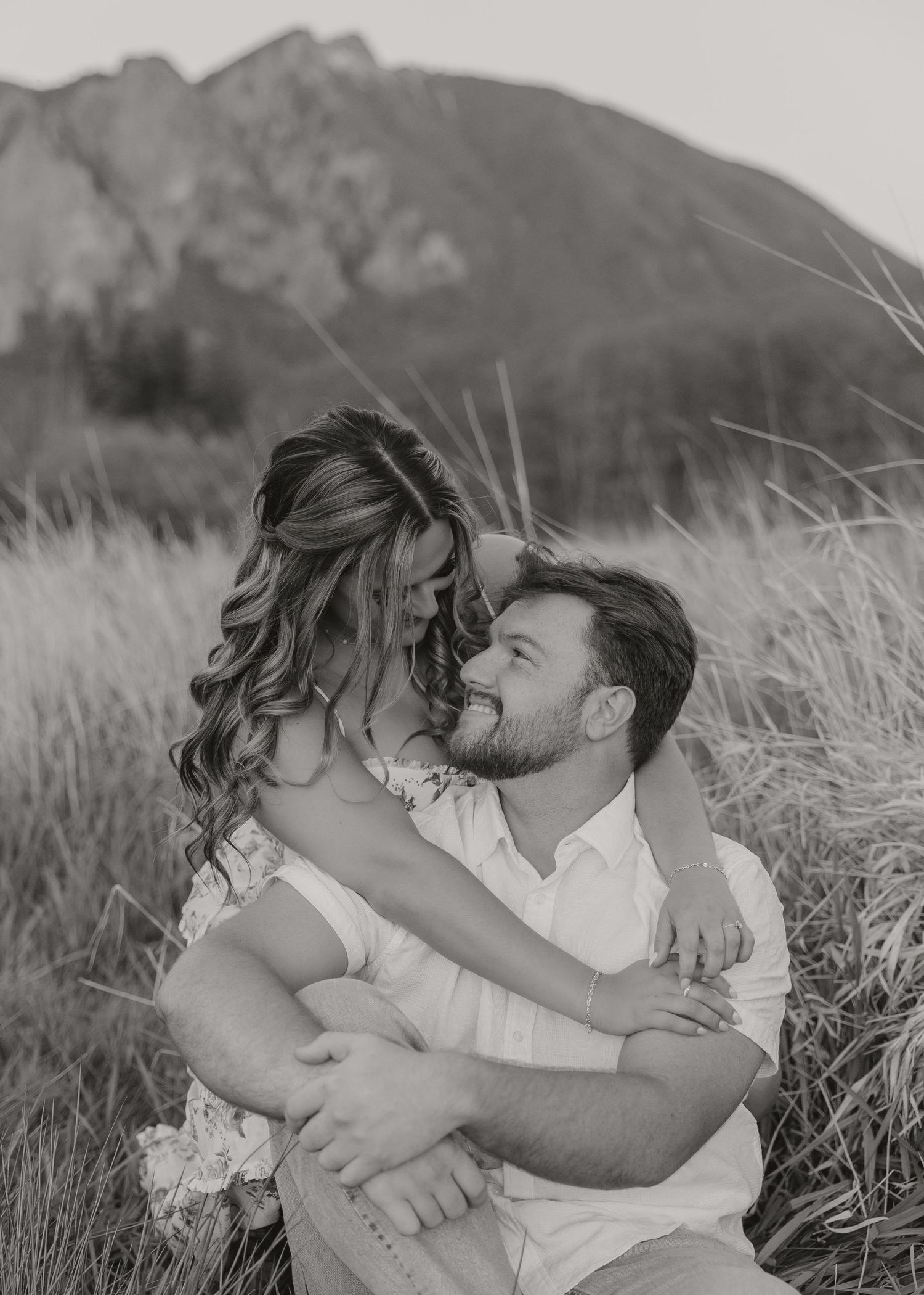 Black and white portrait of couple embracing in mountain meadow.