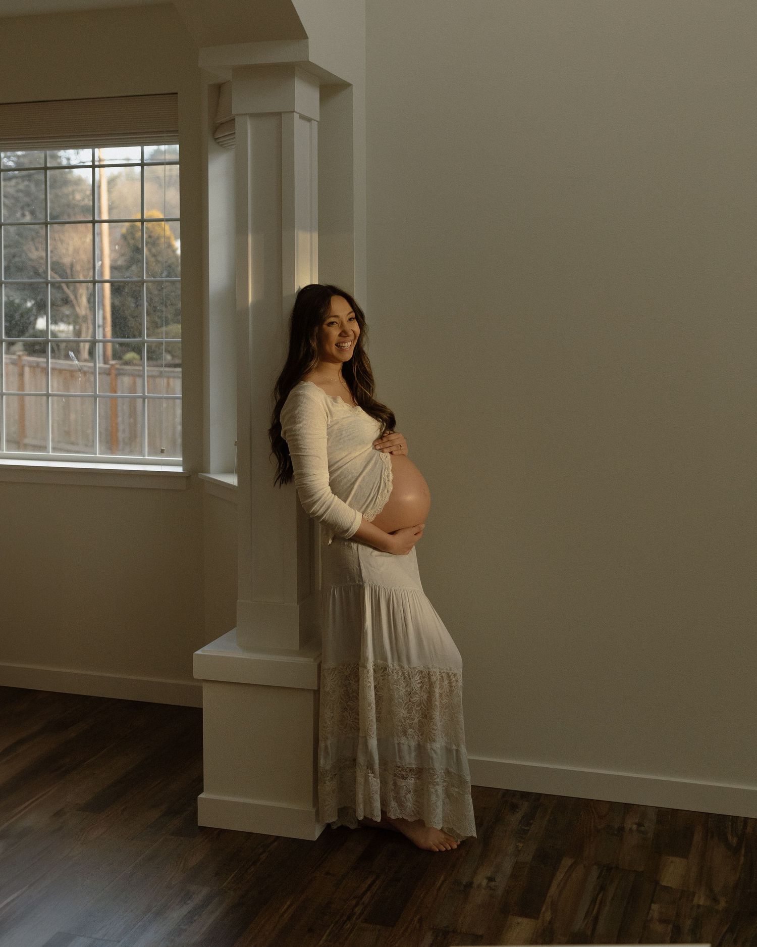 A beautiful maternity portrait by a window with natural light streaming in.
