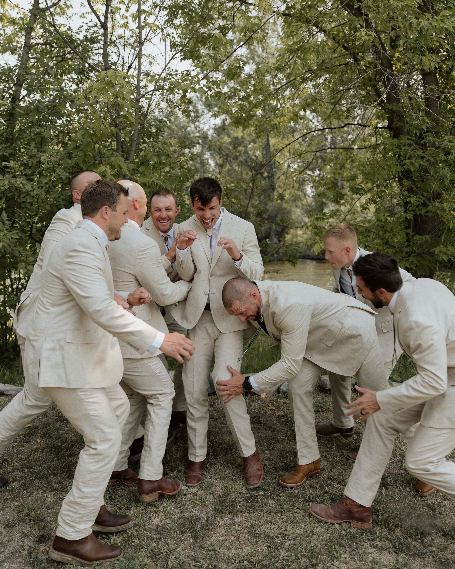 Groomsmen in beige suits laughing and posing together in a playful group photo.