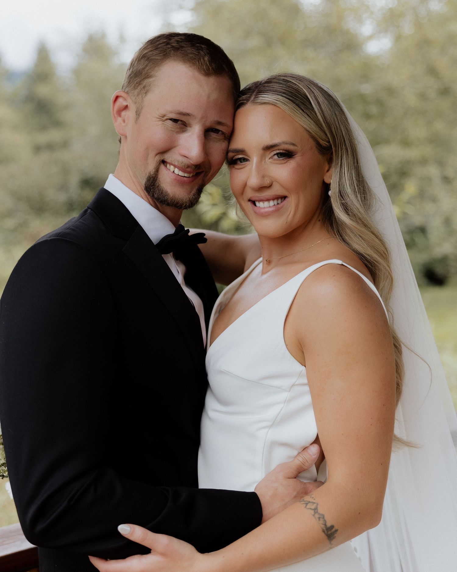 Happy newlyweds share joyful moment in outdoor wedding setting.