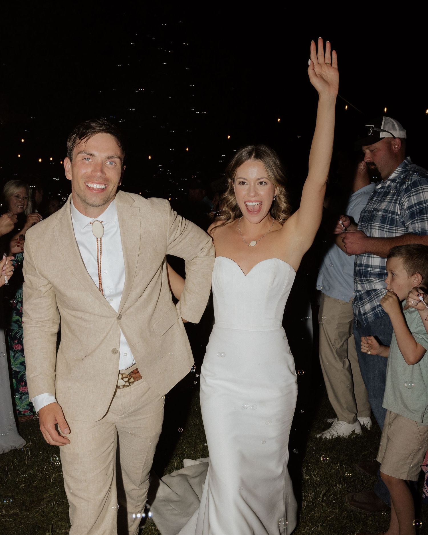 Celebratory moment at outdoor wedding reception with couple showing excitement among guests.