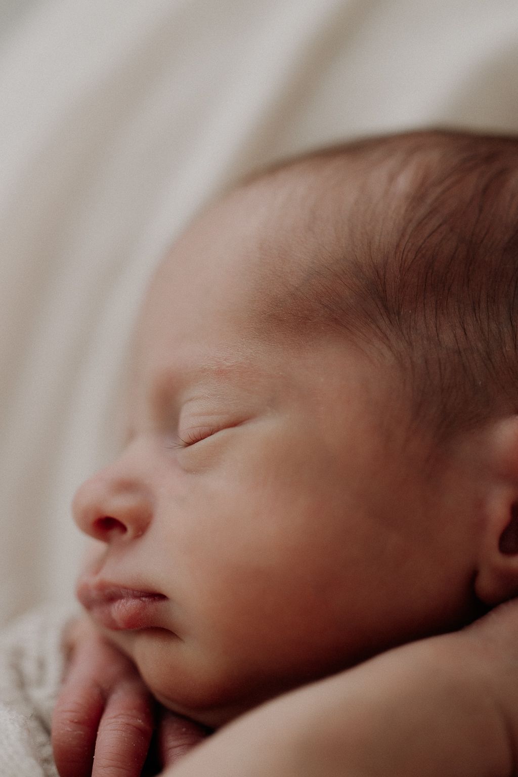 Vastasyntynyt vauva nukkuu viltillä Newborn kuvauksessa studiolla Helsingissä.
