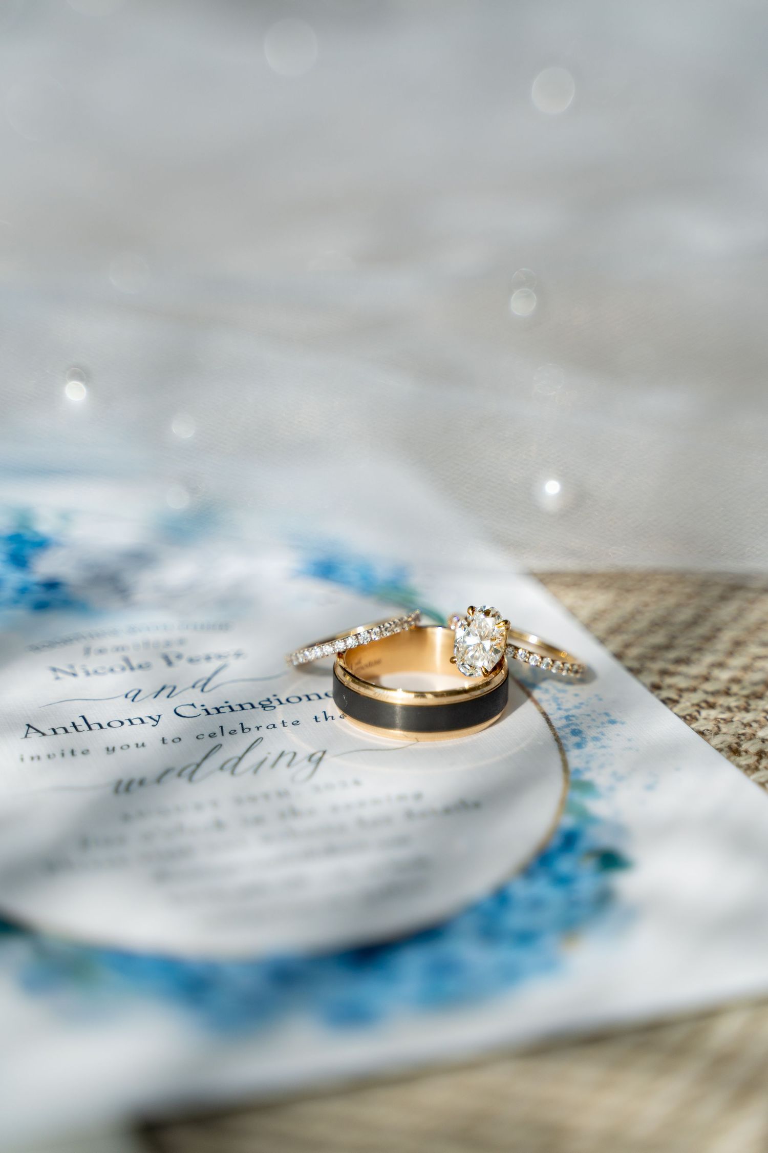 Wedding rings displayed on a watercolor invitation with delicate blue details.