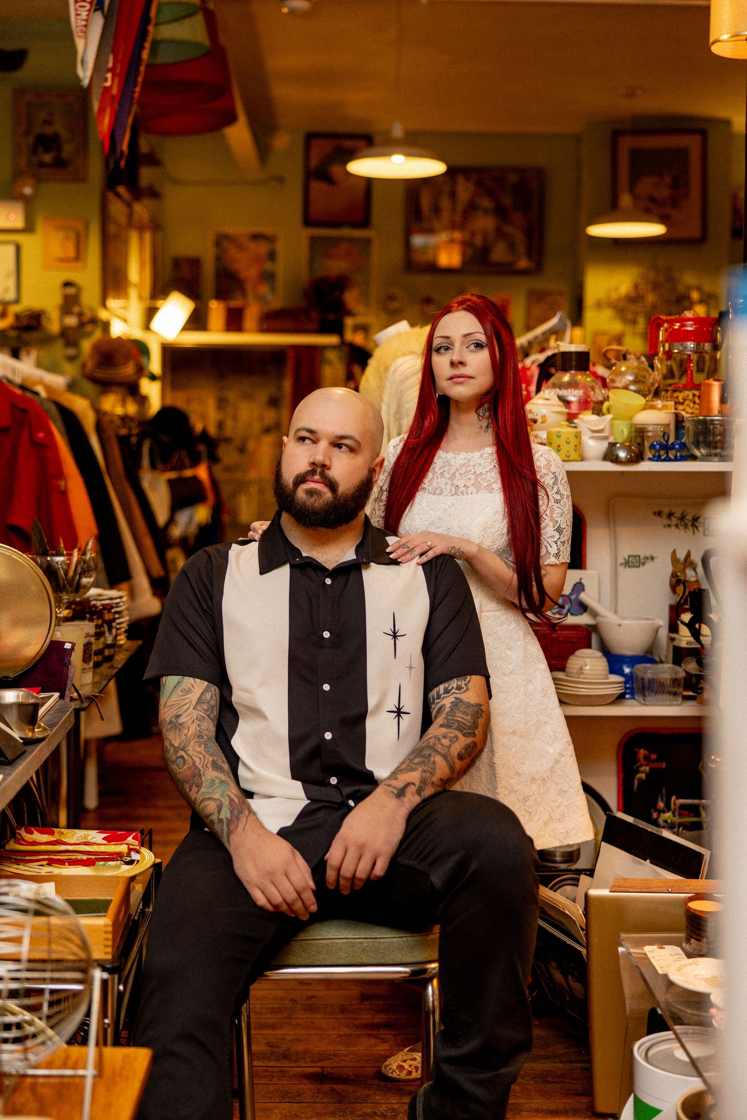 Alternative style couple posing in vintage shop surrounded by collectibles and memorabilia.