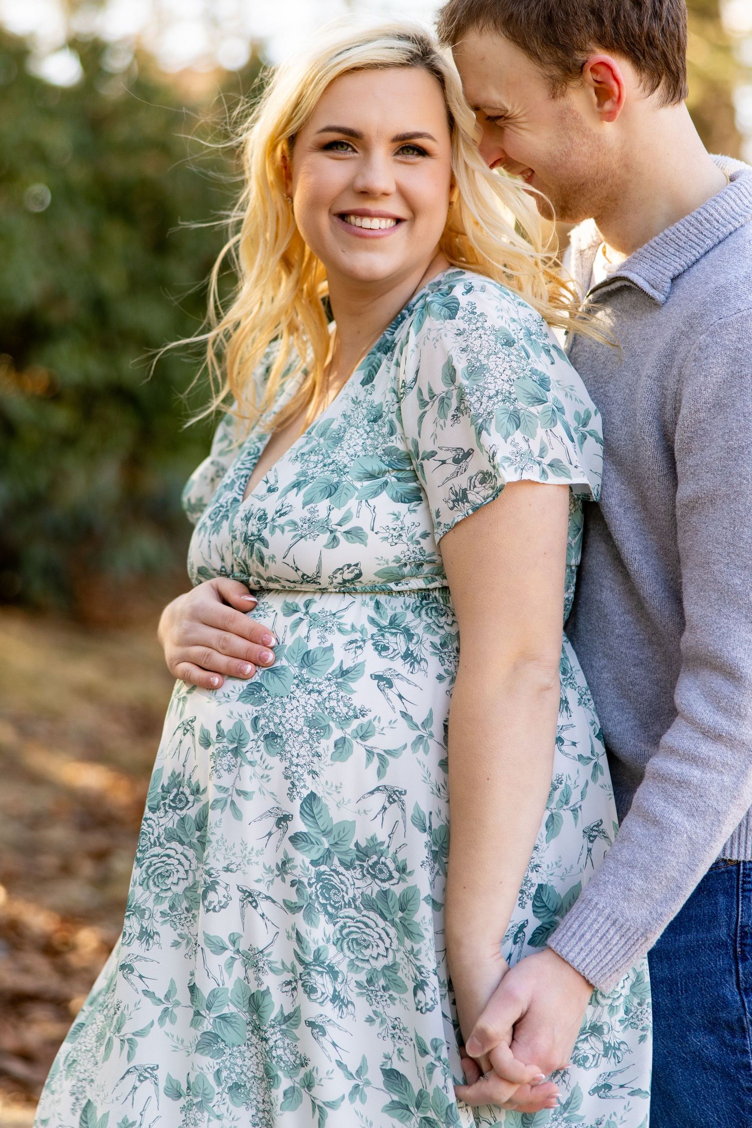A couple shares an intimate moment in a floral dress and sweater during an outdoor photoshoot.