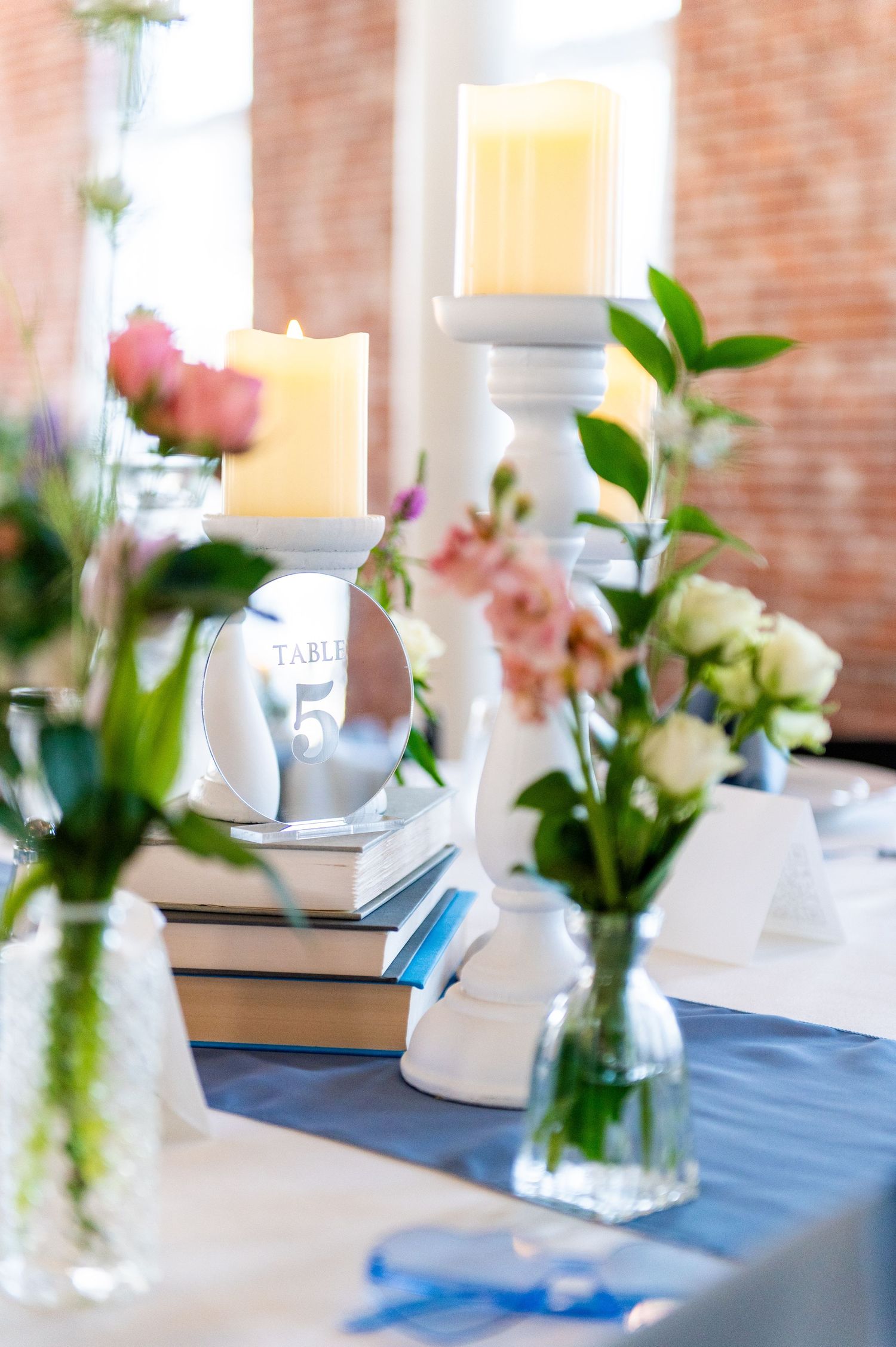Elegant table setting with white candles, blue accents, and fresh floral arrangements.
