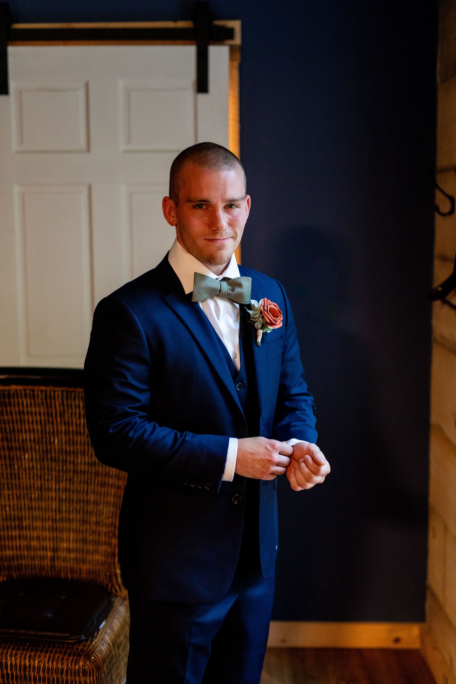Groom wearing classic navy suit and bow tie poses in formal portrait.
