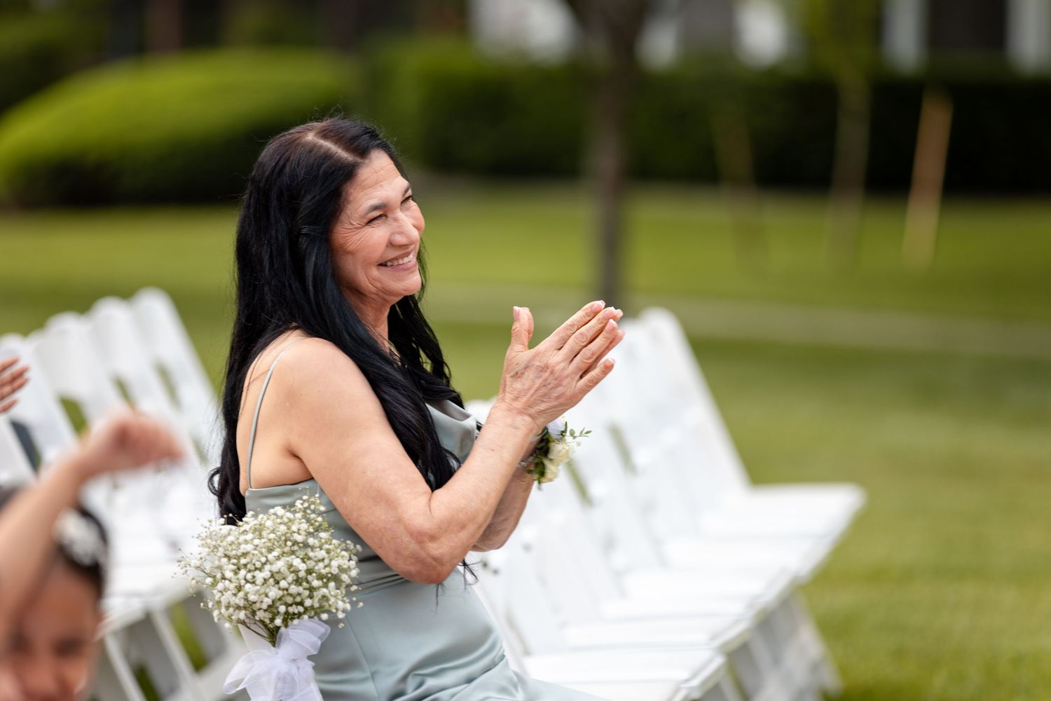 Wedding guests shower happy couple with confetti while celebrating outdoors in a green garden setting.