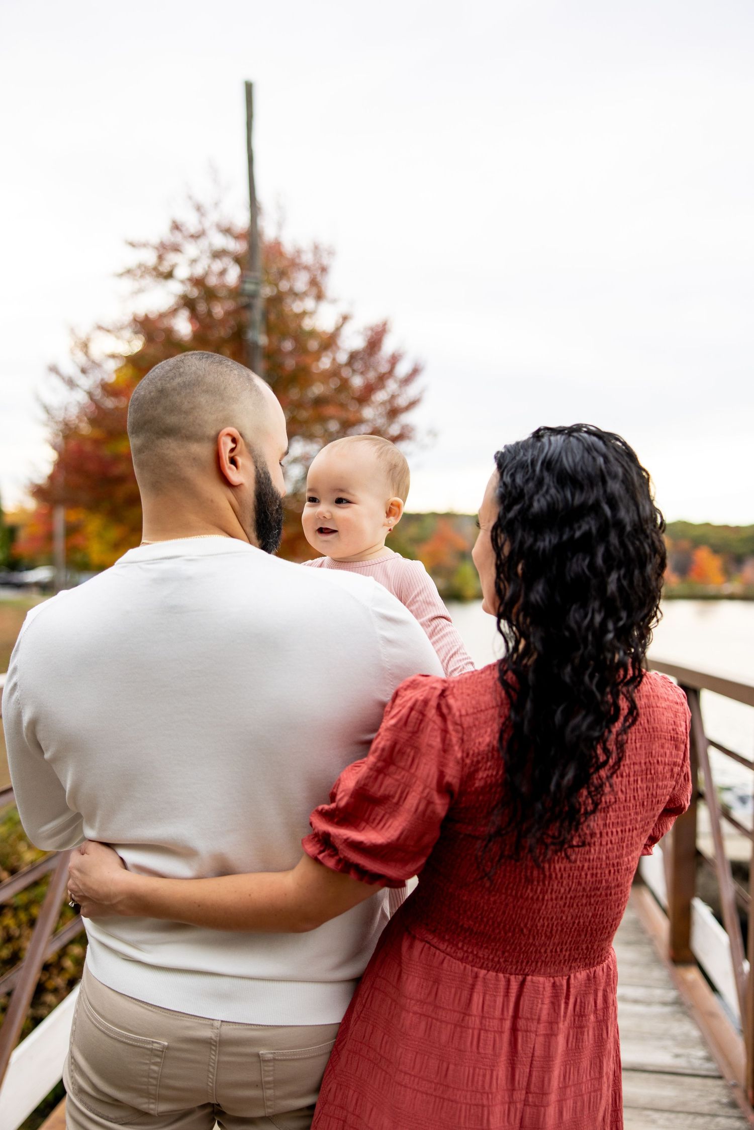 Family shares intimate moment on bridge surrounded by fall colors.