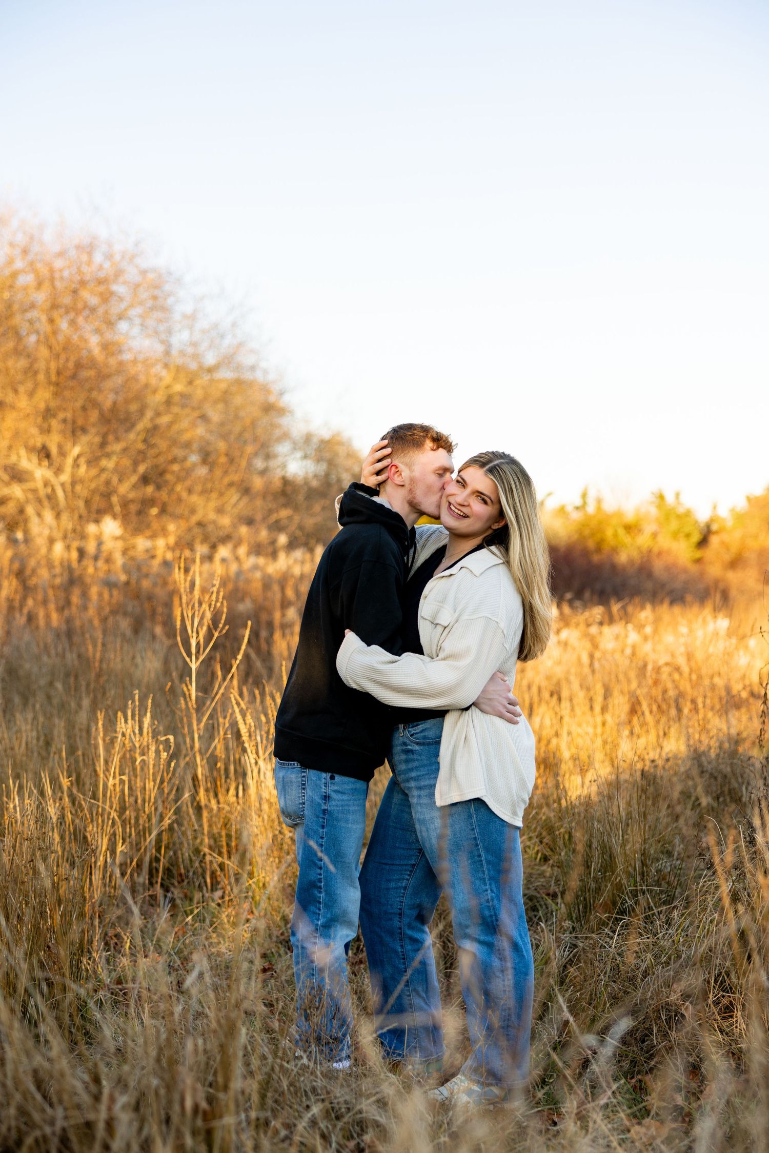 Couple embracing in golden autumn field during sunset.