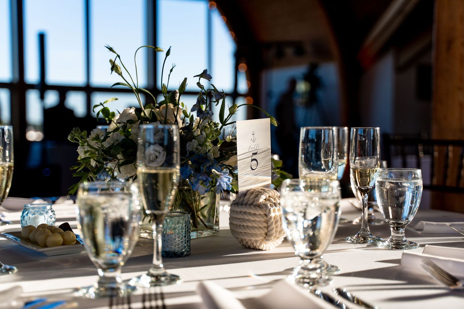 Elegant wedding reception table setting with floral centerpiece and champagne glasses.