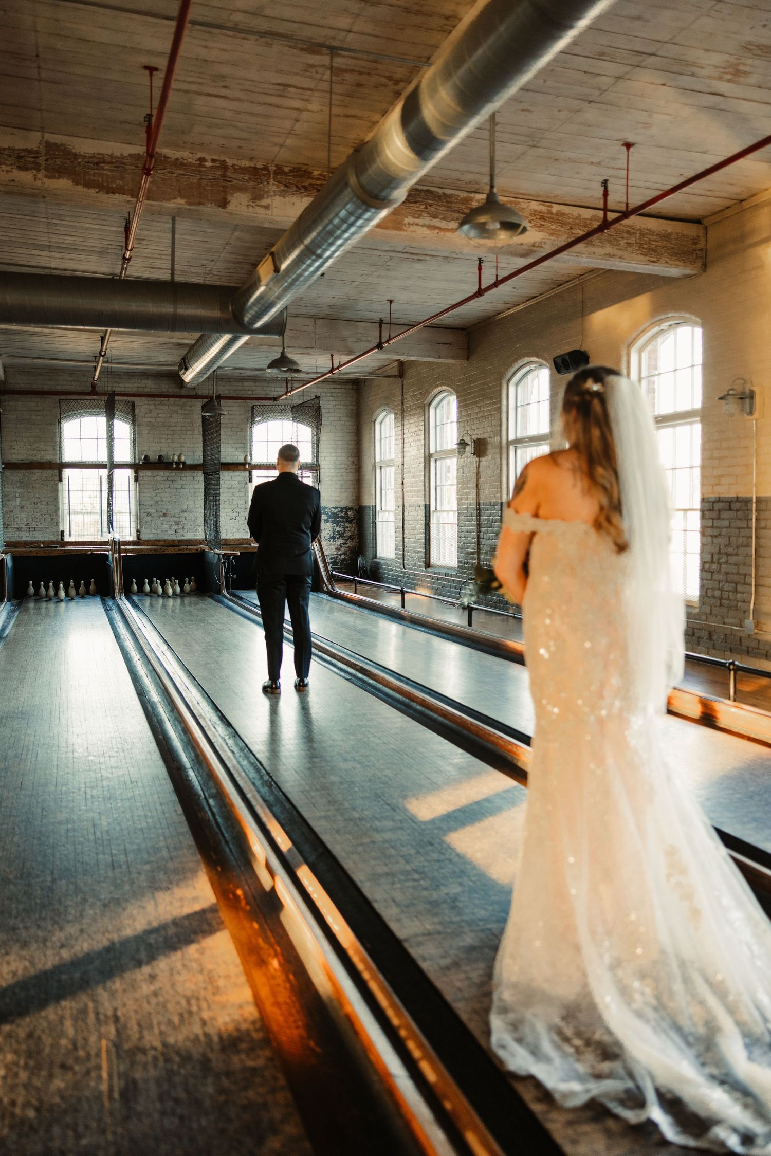 Wedding couple in vintage bowling alley with dramatic lighting.