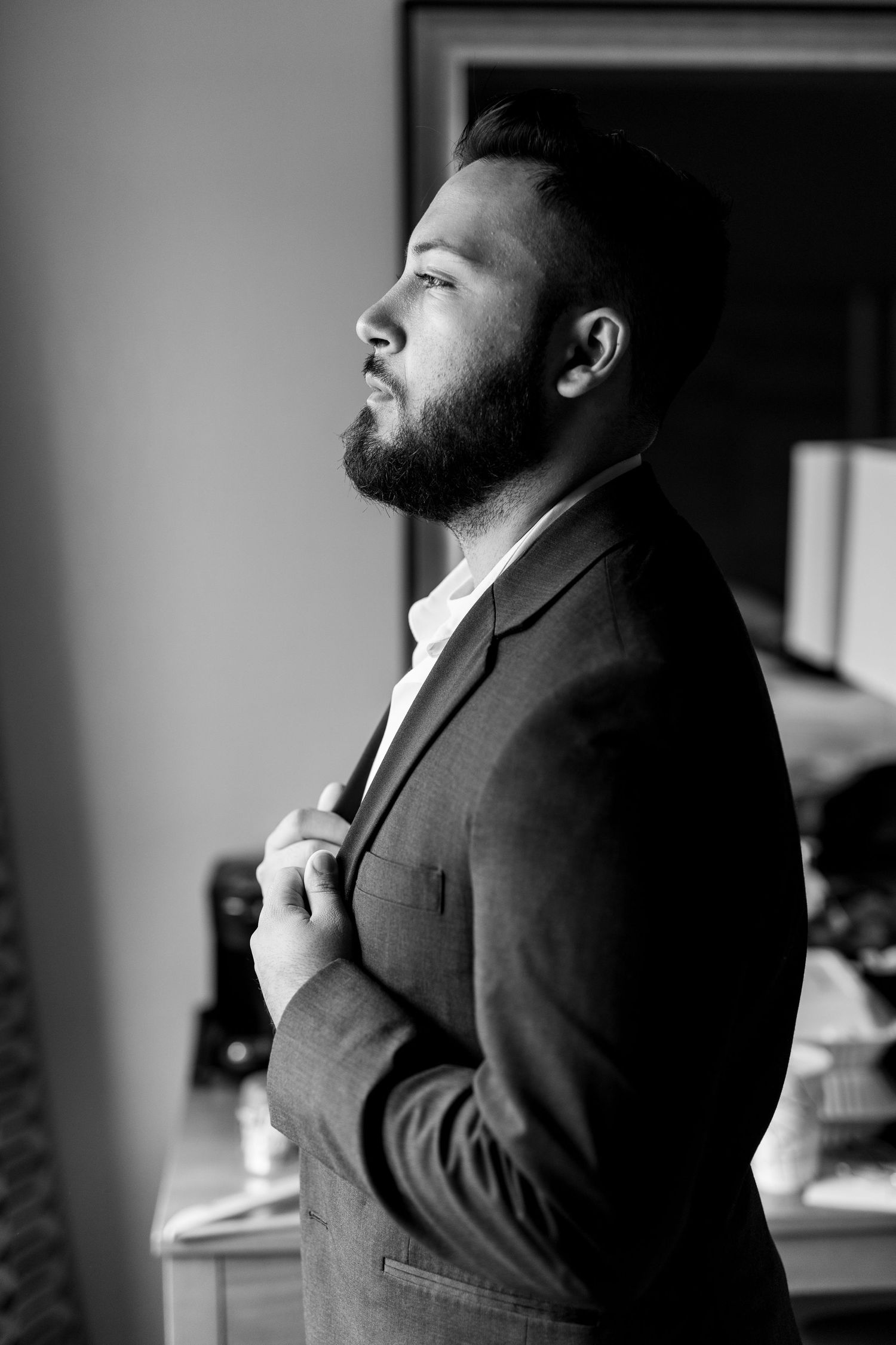 Professional black and white portrait of a bearded man in a suit looking to the side.