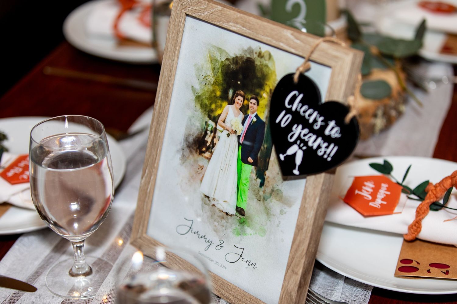 Wedding table setting with framed photo and wine glass at reception.