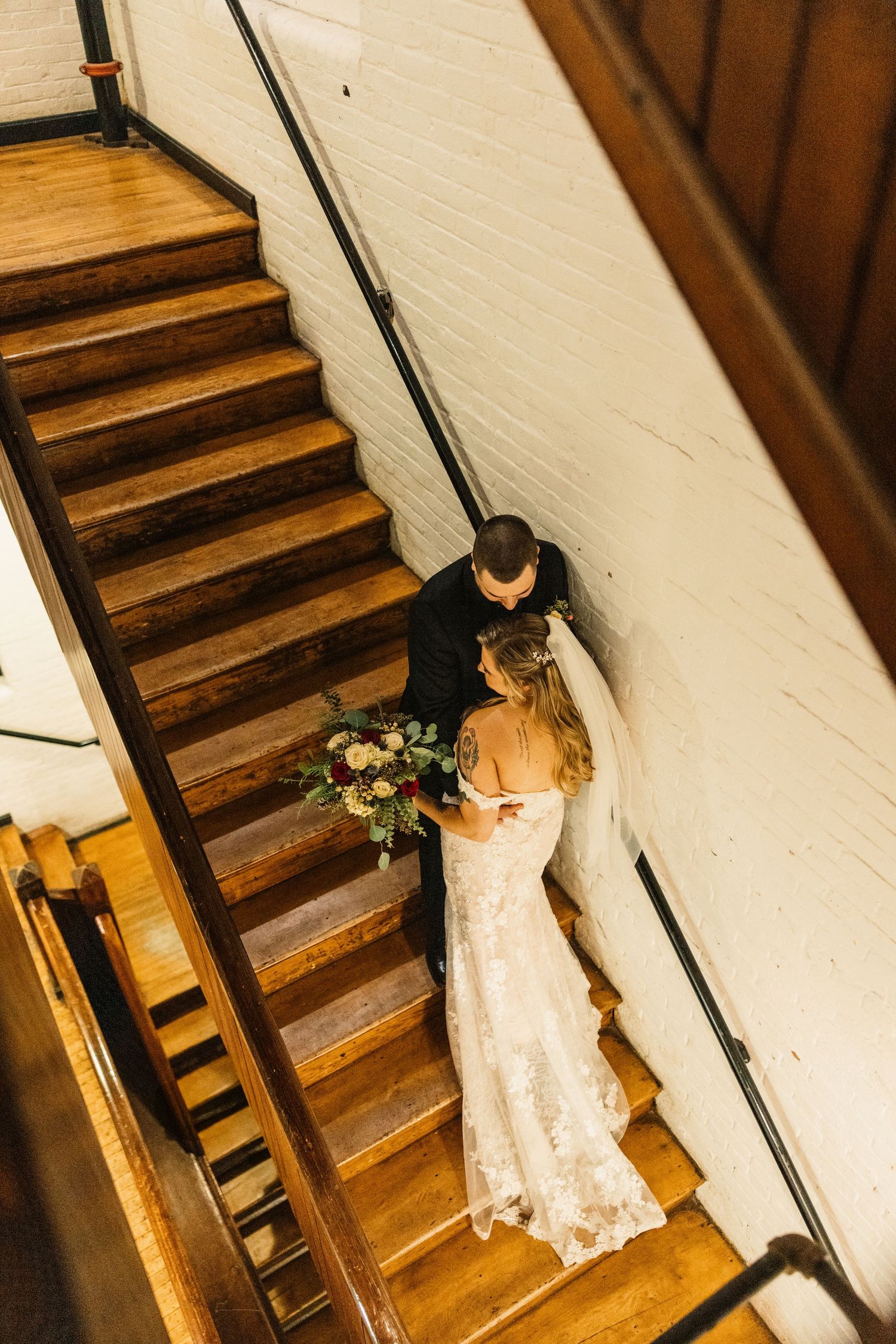 A couple shares an intimate moment on wooden stairs during their winter wedding.