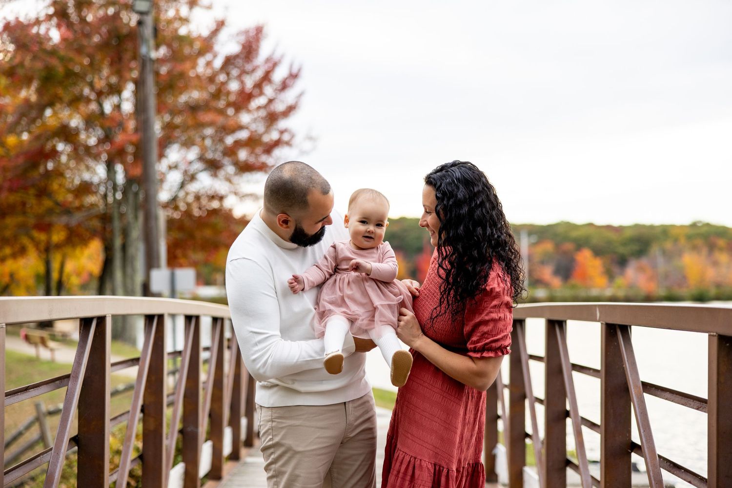 Family sharing a tender moment together on wooden bridge during fall season.