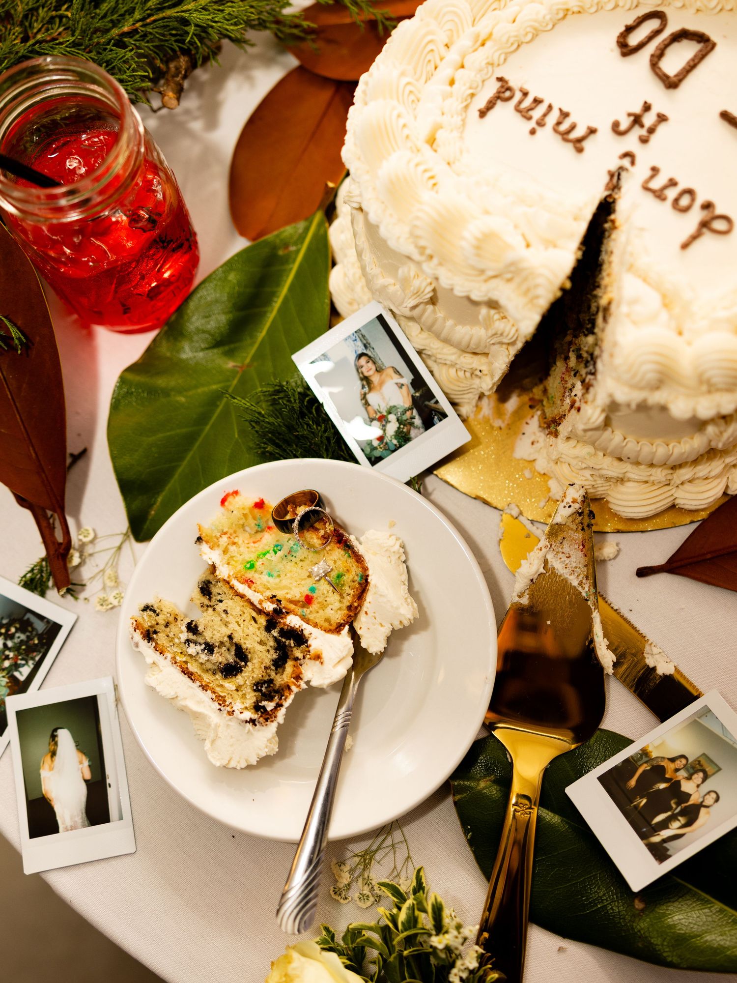 Wedding cake and celebration details with polaroid photos and a red cocktail on a decorated table.