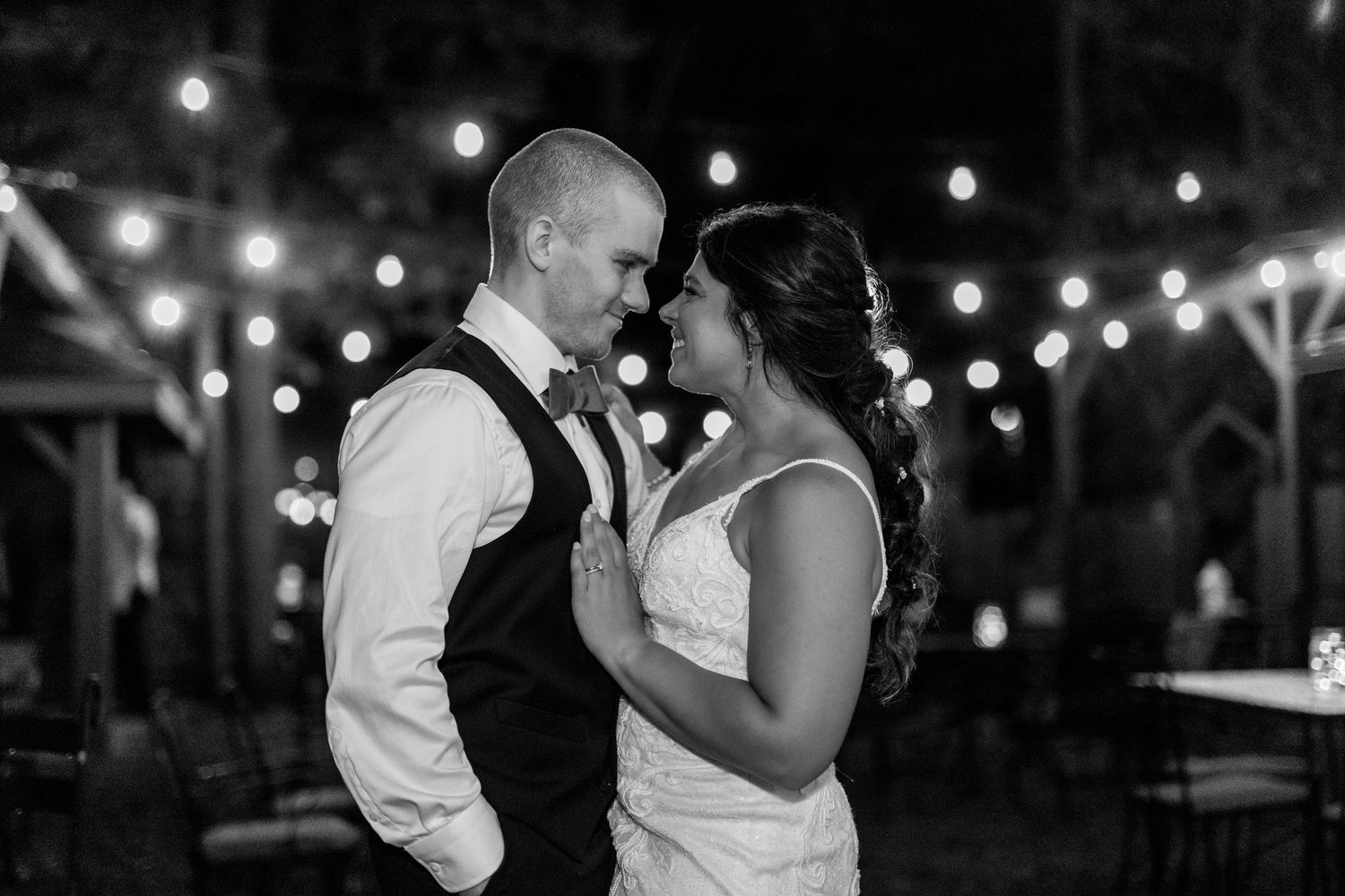 A couple shares an intimate moment on the dance floor with twinkling lights in the background.