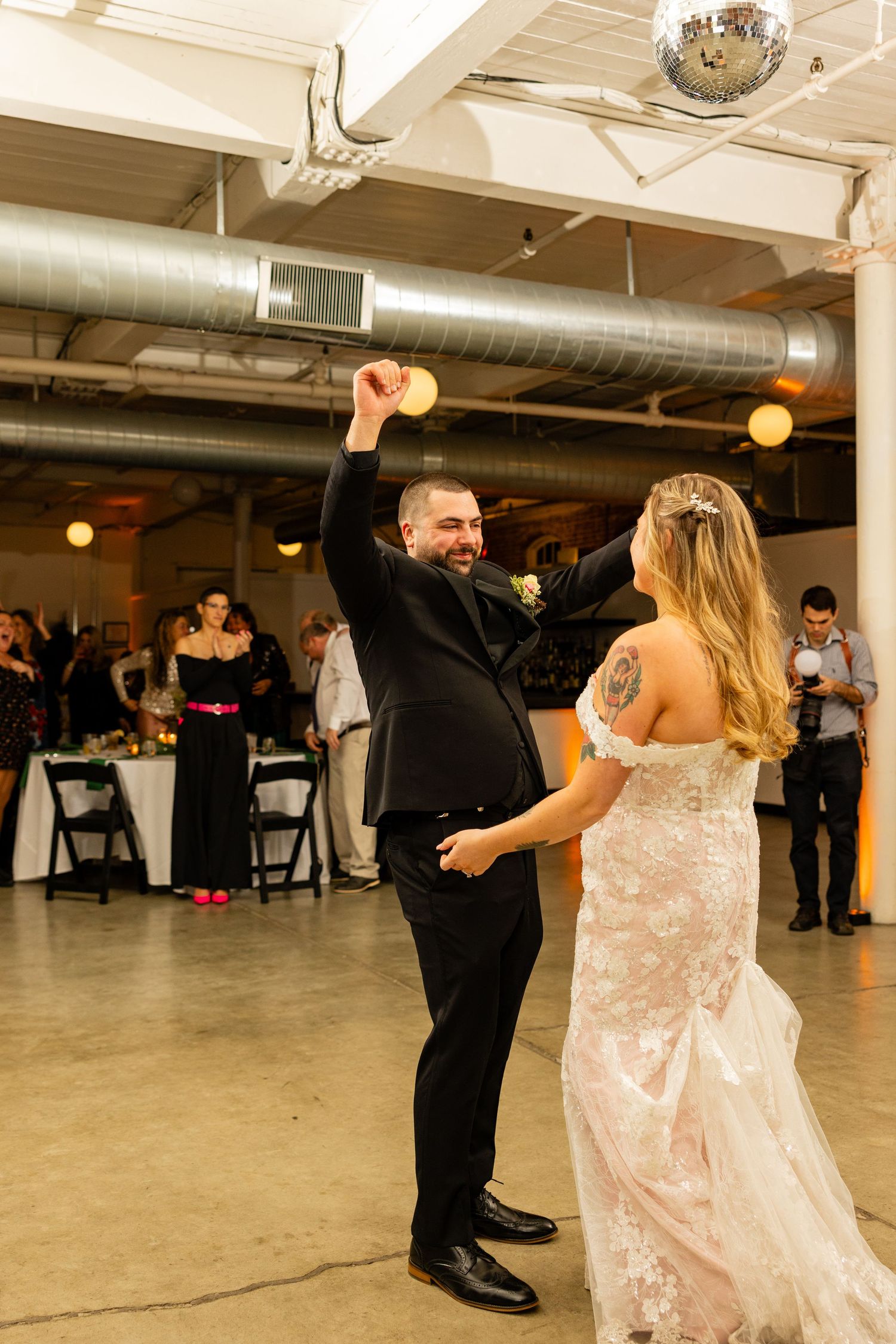 Couple dancing at their wedding reception in an industrial-style venue with exposed ductwork.