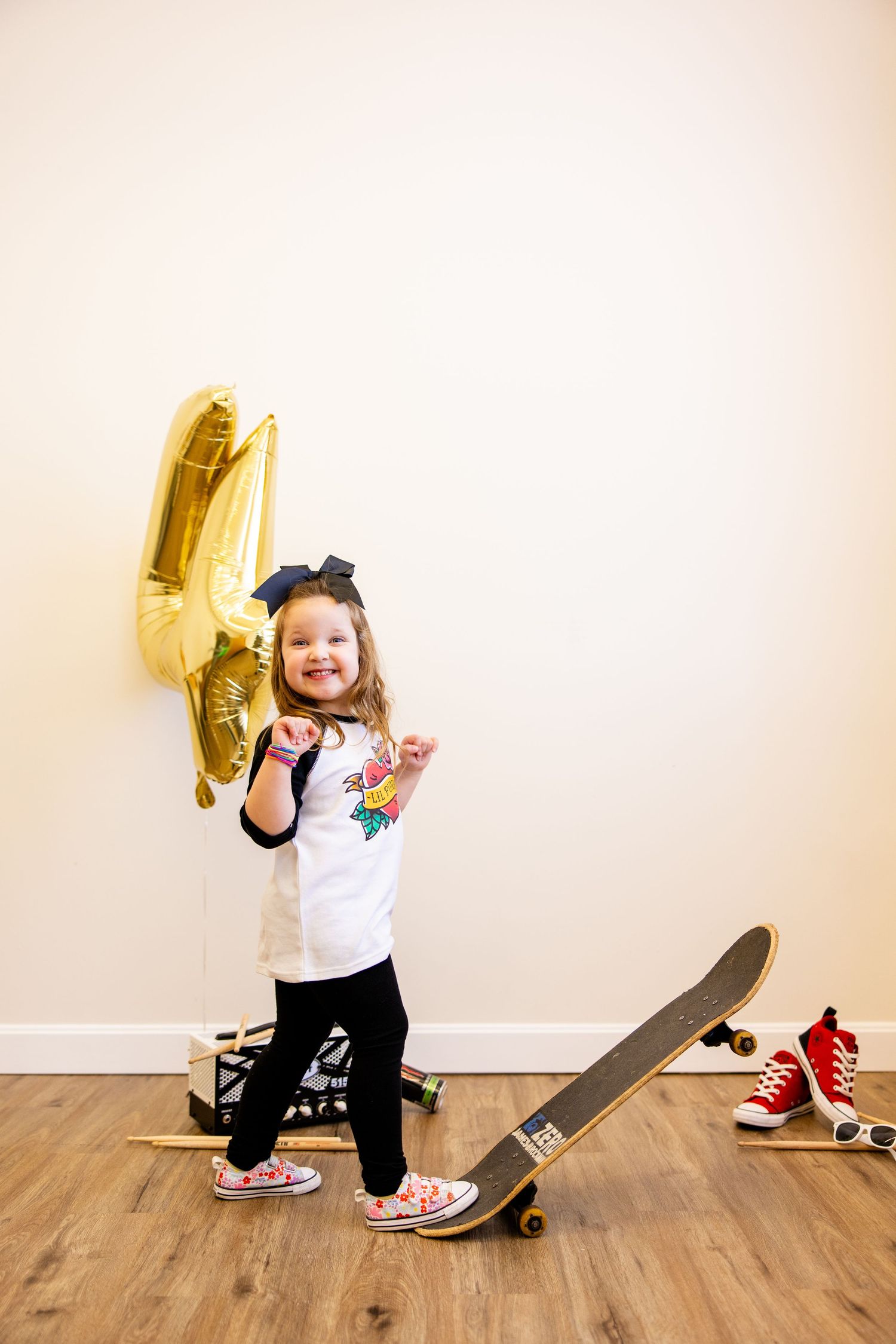 A playful scene with skateboard, red sneakers, and gold balloon against hardwood floors.