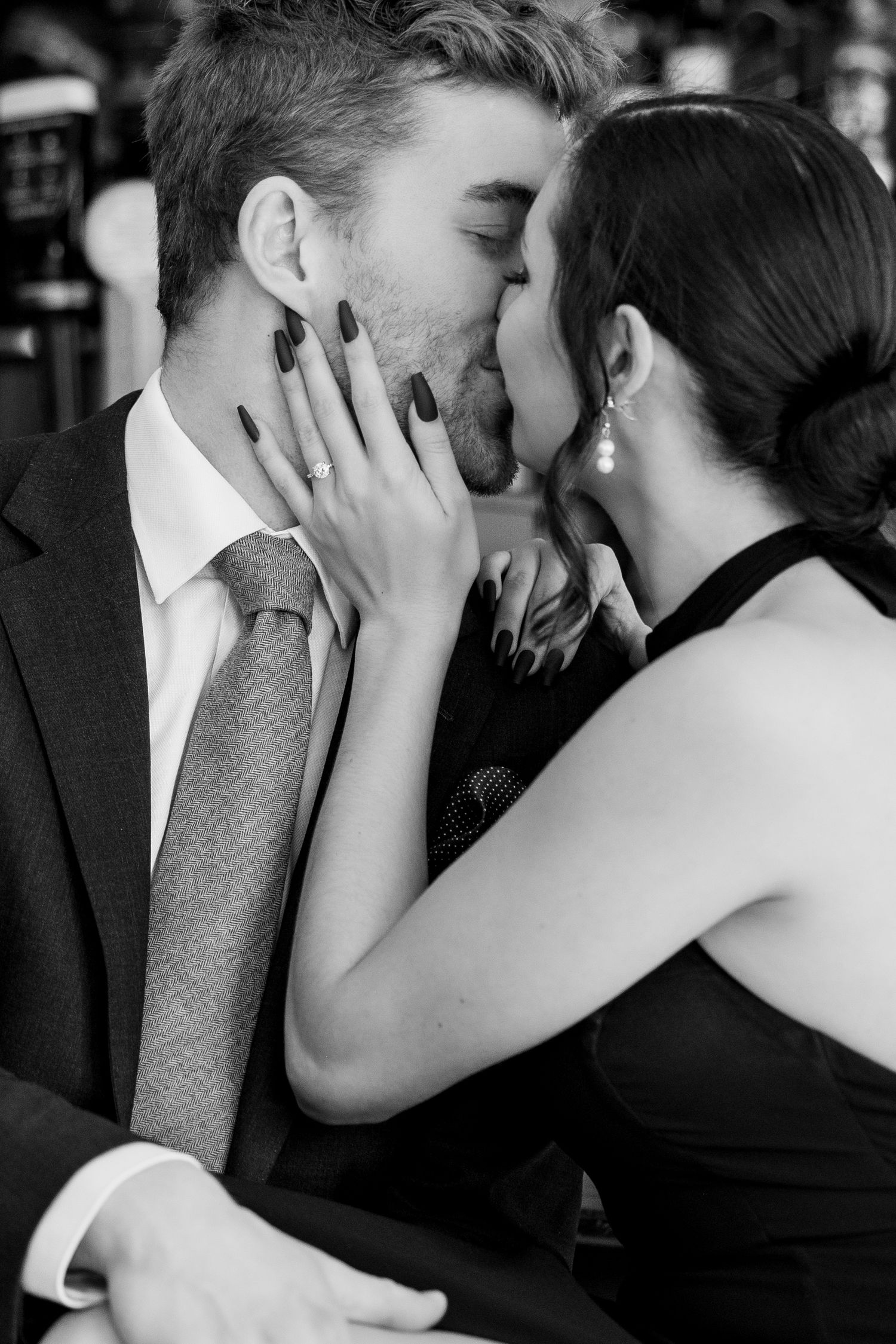 A romantic black and white photo captures an intimate kiss at a bar.