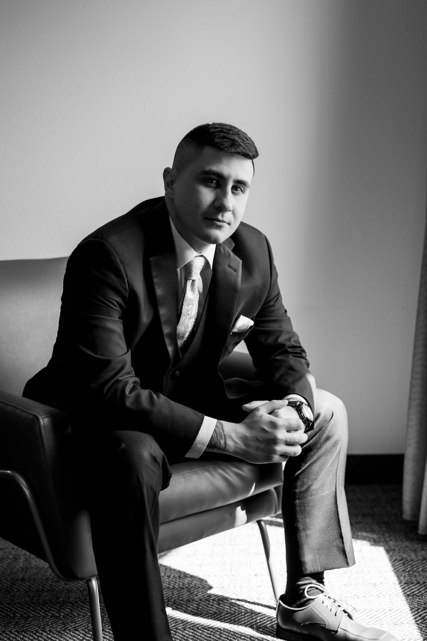 Classic black and white portrait of a man in a formal suit seated on a chair.