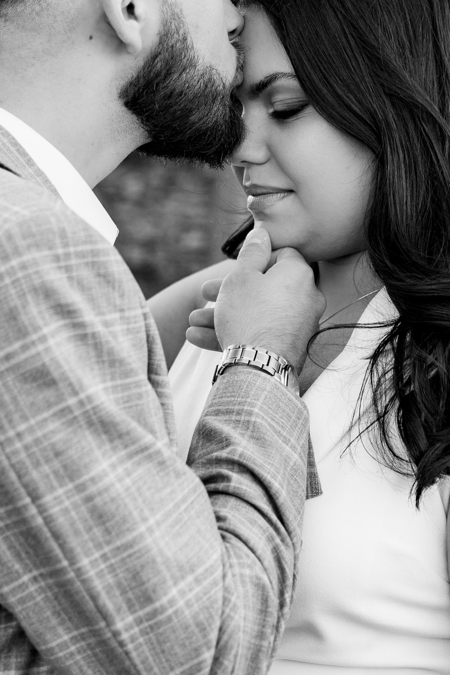 An intimate black and white portrait of a couple sharing a tender moment.