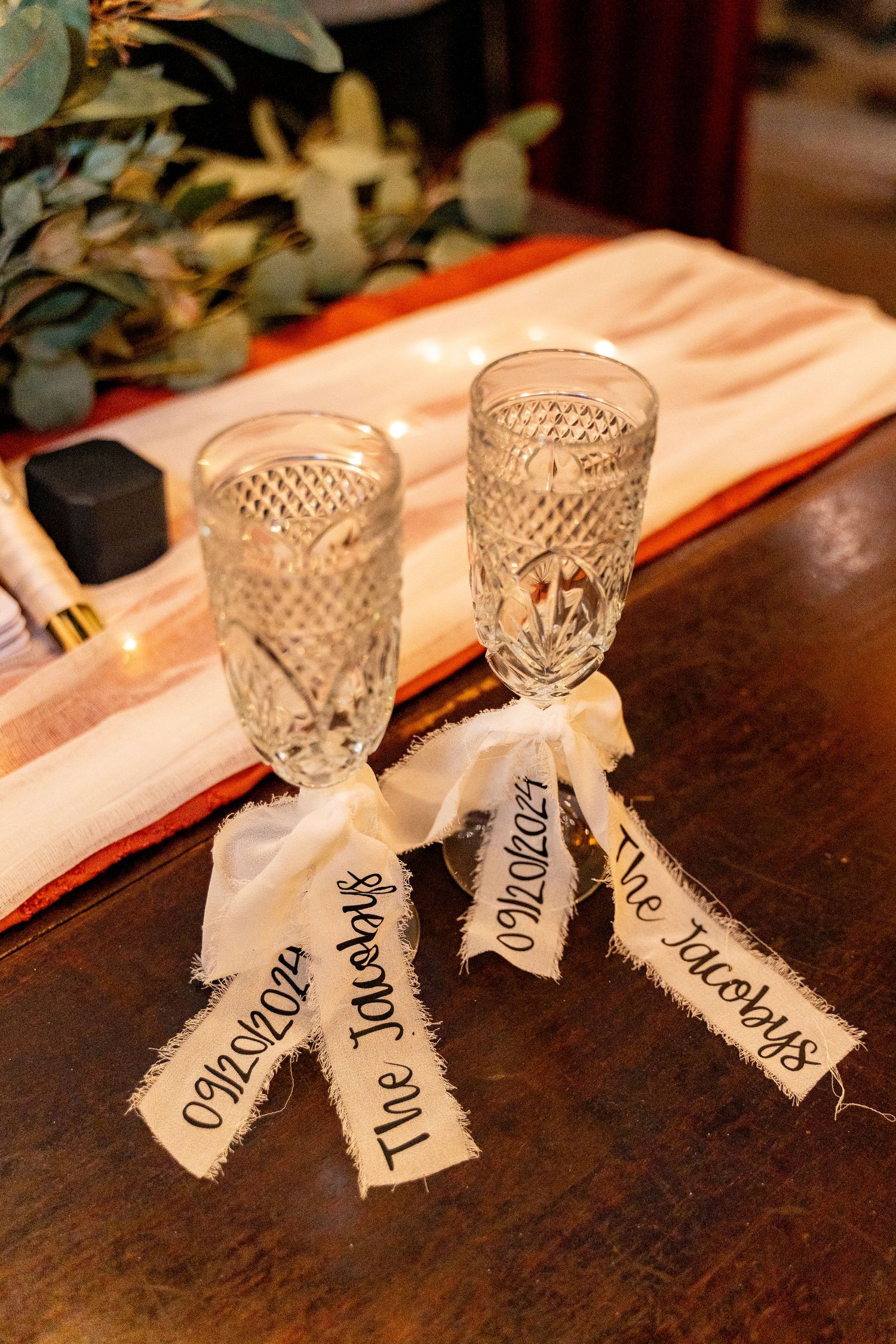 Vintage crystal champagne glasses decorated with fabric name tags for wedding toast.