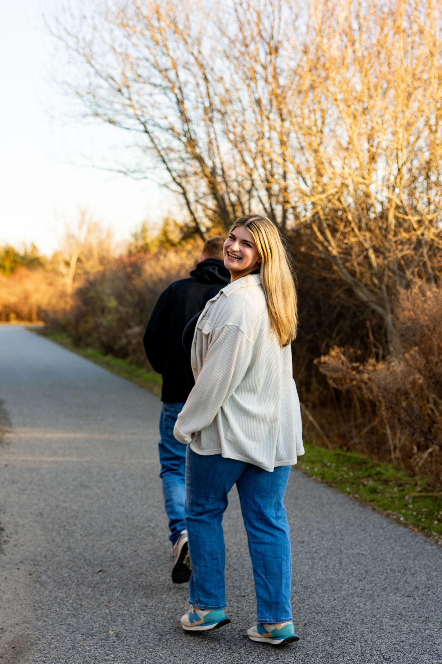 Person looking back at camera while walking on path during golden hour.