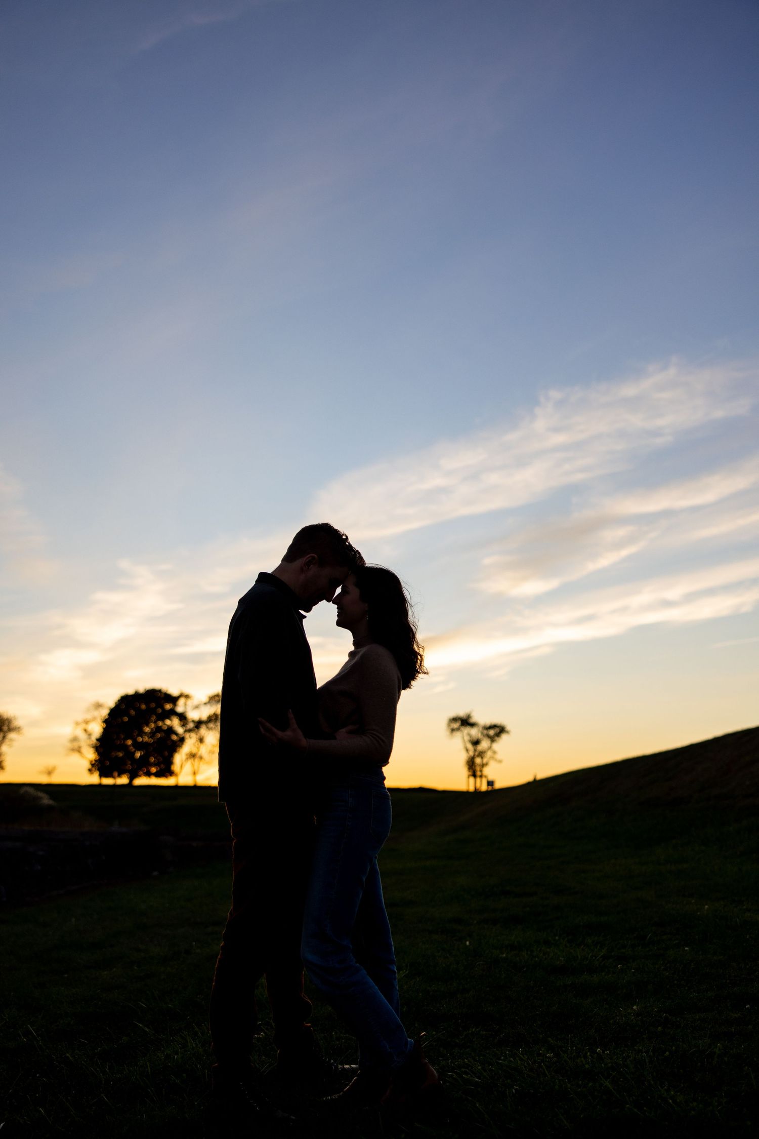 A silhouetted couple embraces against a dramatic sunset sky.