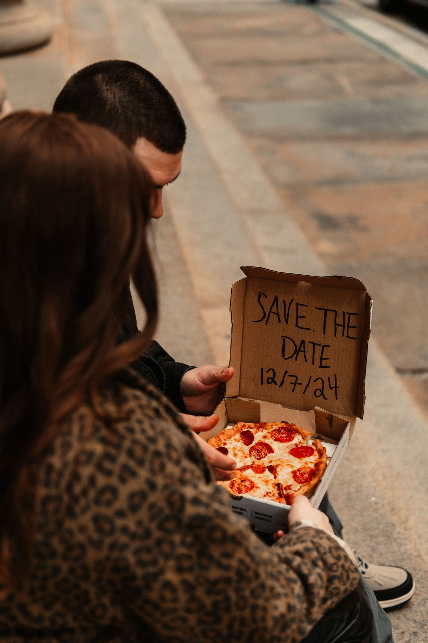 Pizza box with 'Save the Date' message being shared between couple.