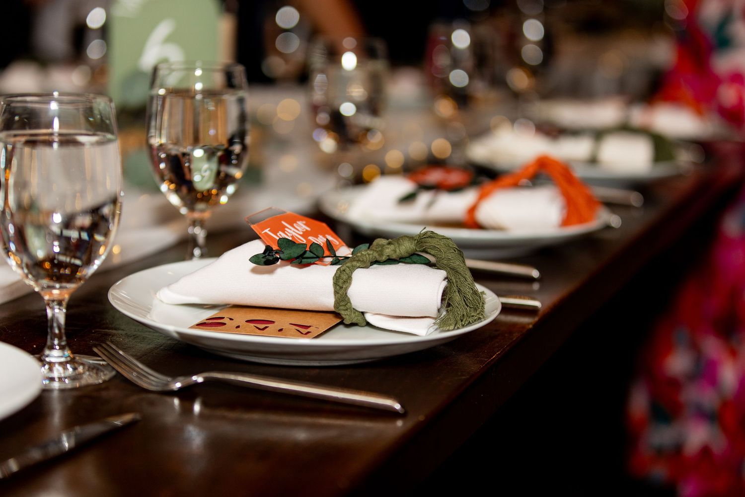 Elegant place setting at formal dinner with wine glasses and plated meal.