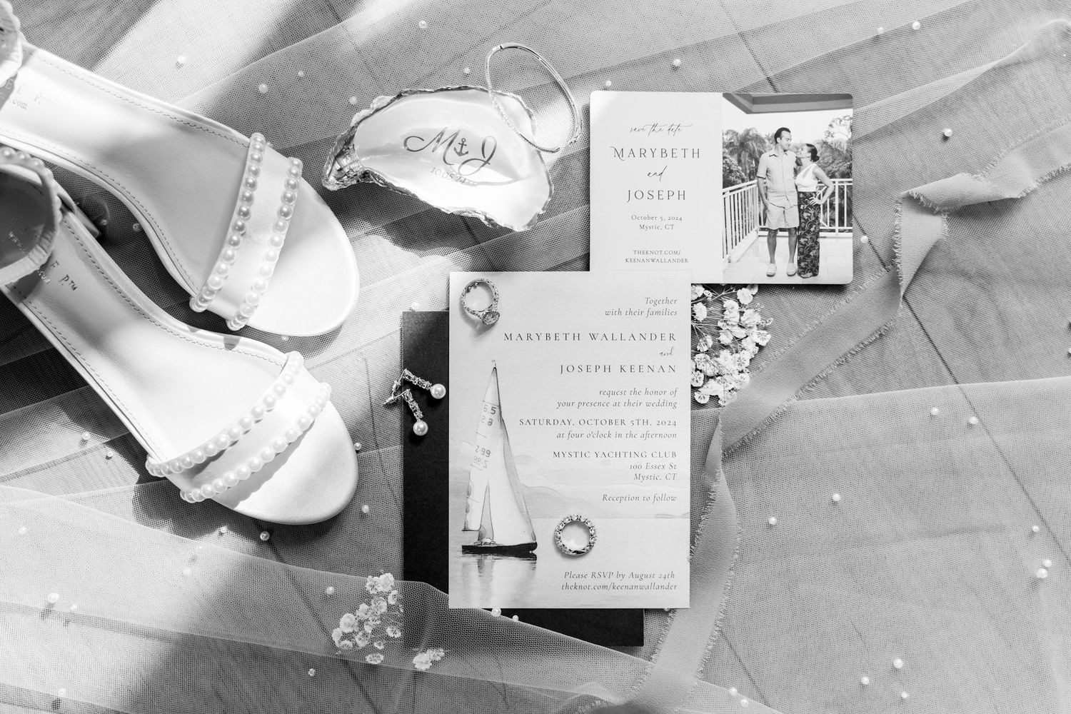 Black and white image of wedding invitation and bridal shoes on lace fabric.