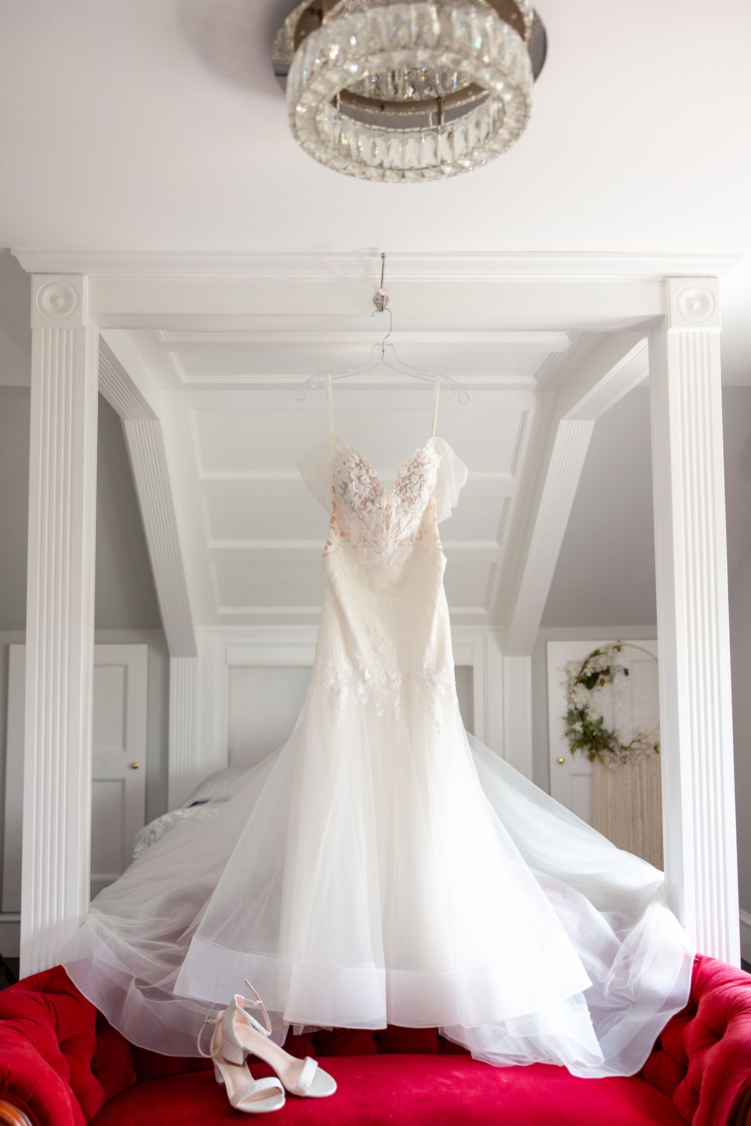 Multiple elegant white wedding dresses displayed on red velvet showcasing their flowing tulle skirts and delicate details.