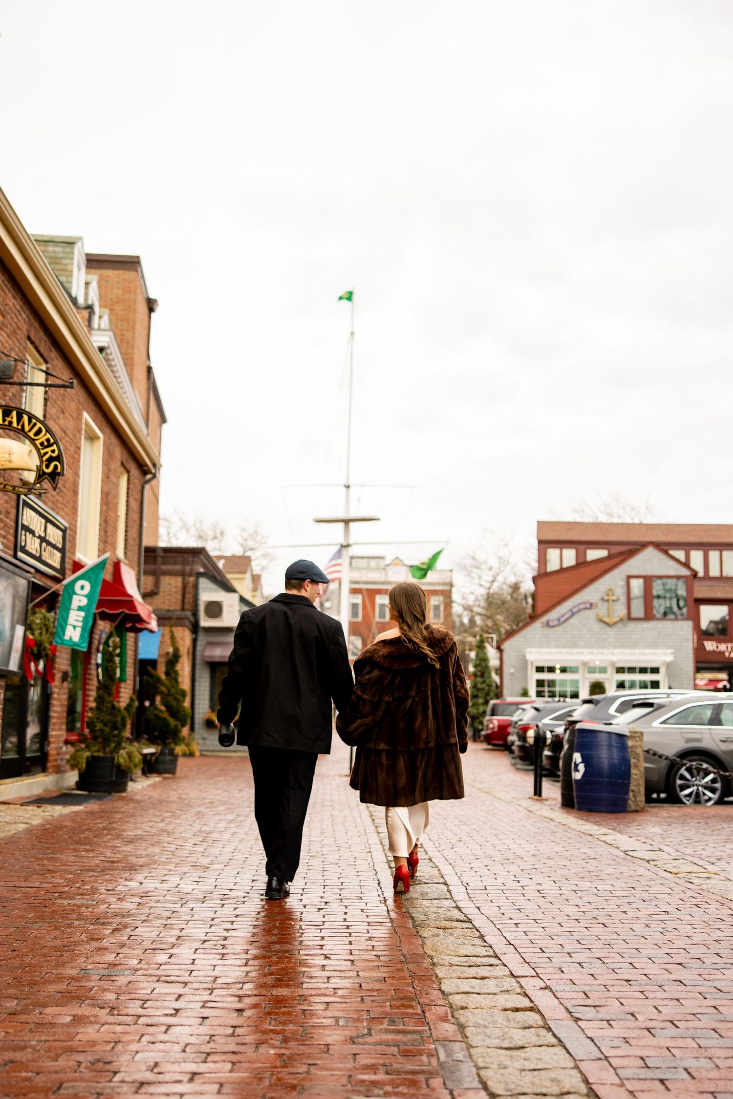 Couple walking down a brick paved street with historic buildings and flags visible.